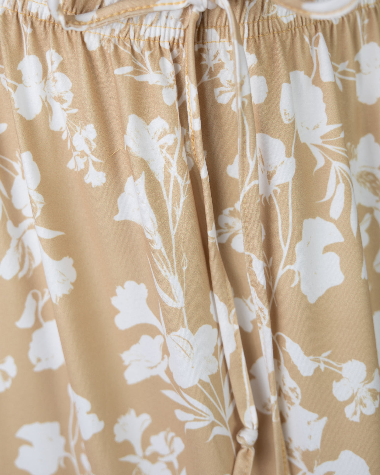 Closeup Shot of the tie of the waistband on a yellow floral skirt.