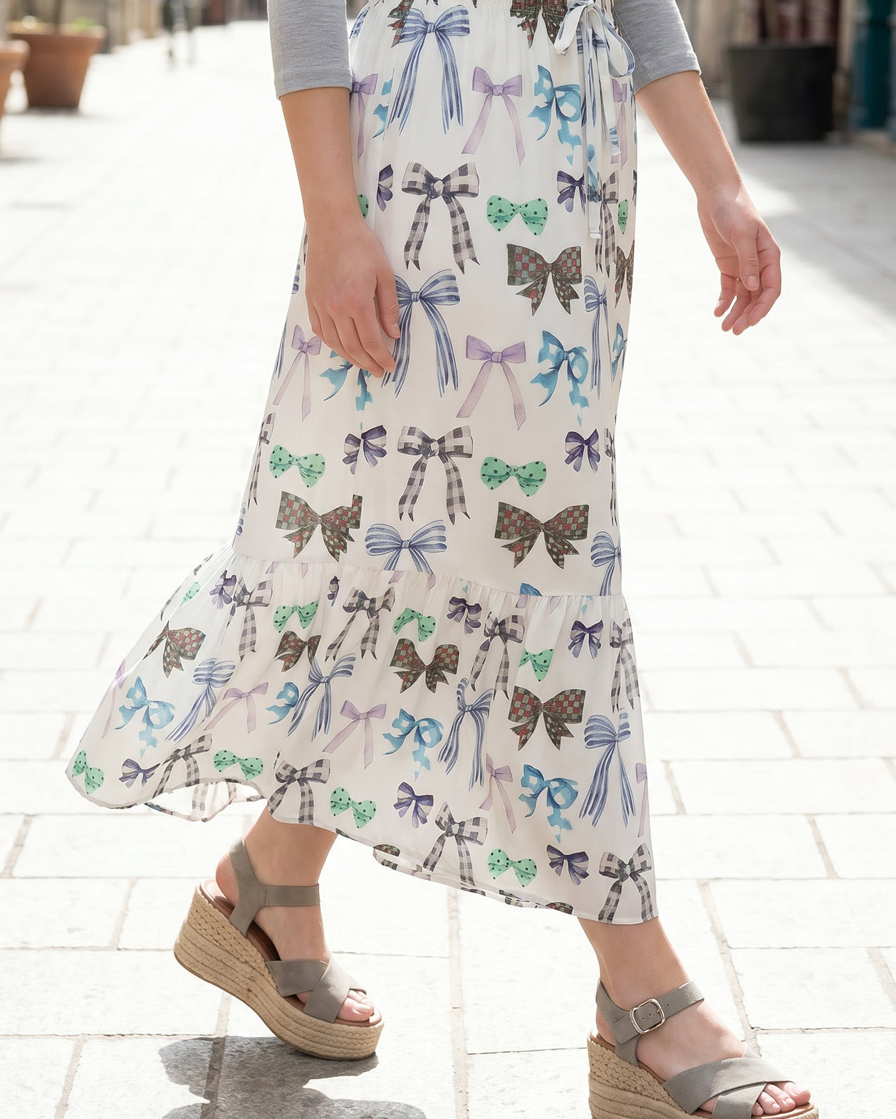 Person wearing a maxi skirt with a bow pattern.