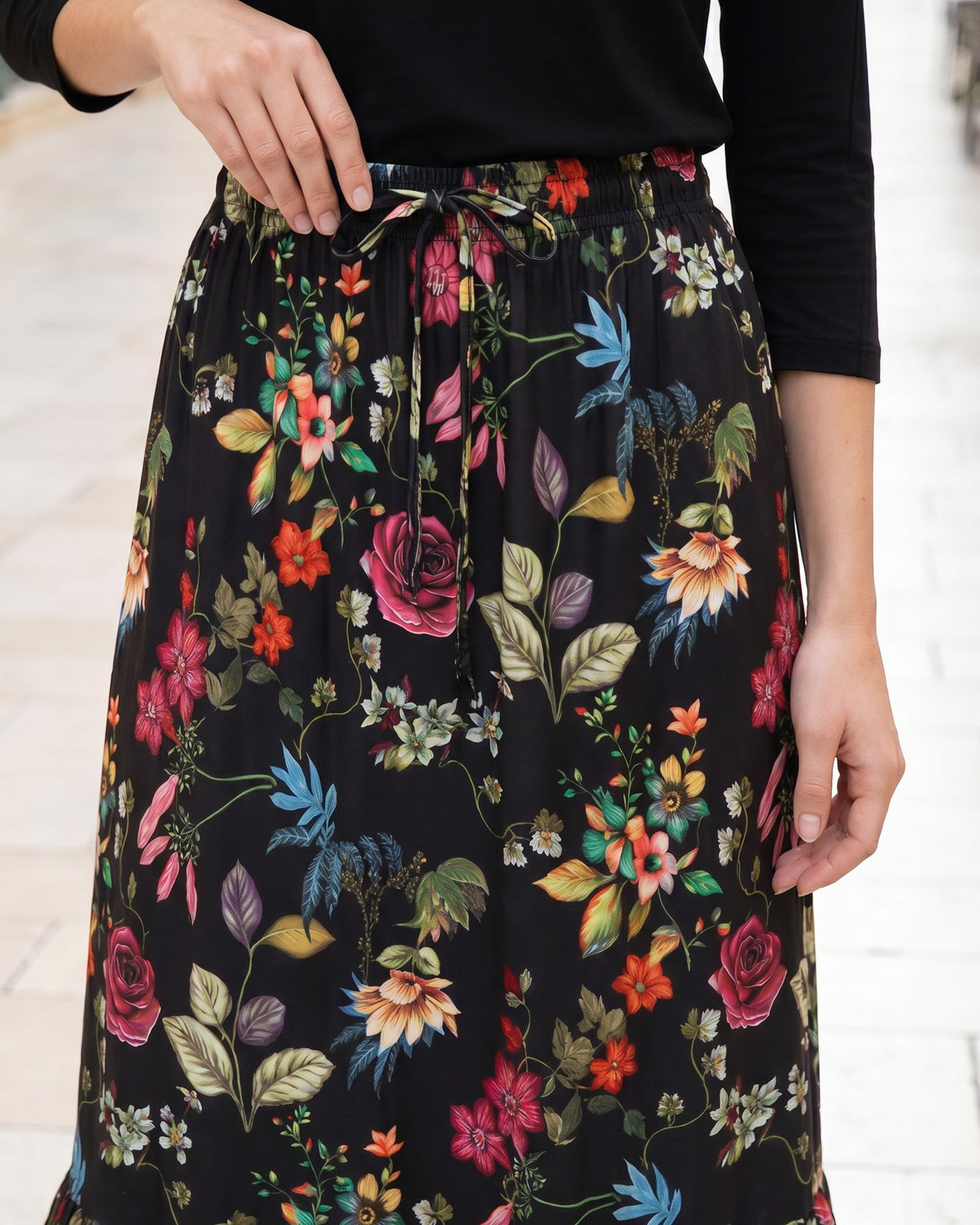 Person wearing a black floral skirt with a white background