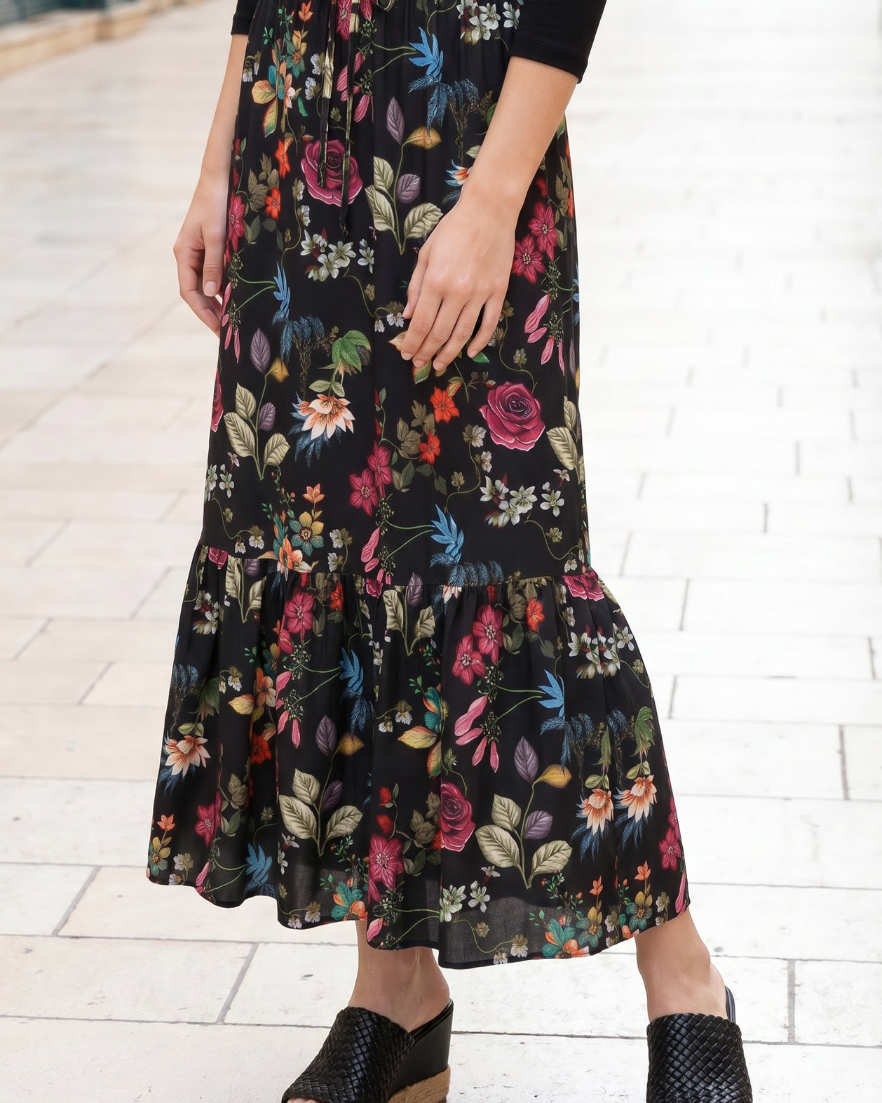 Person wearing a long floral skirt on a white tiled floor.