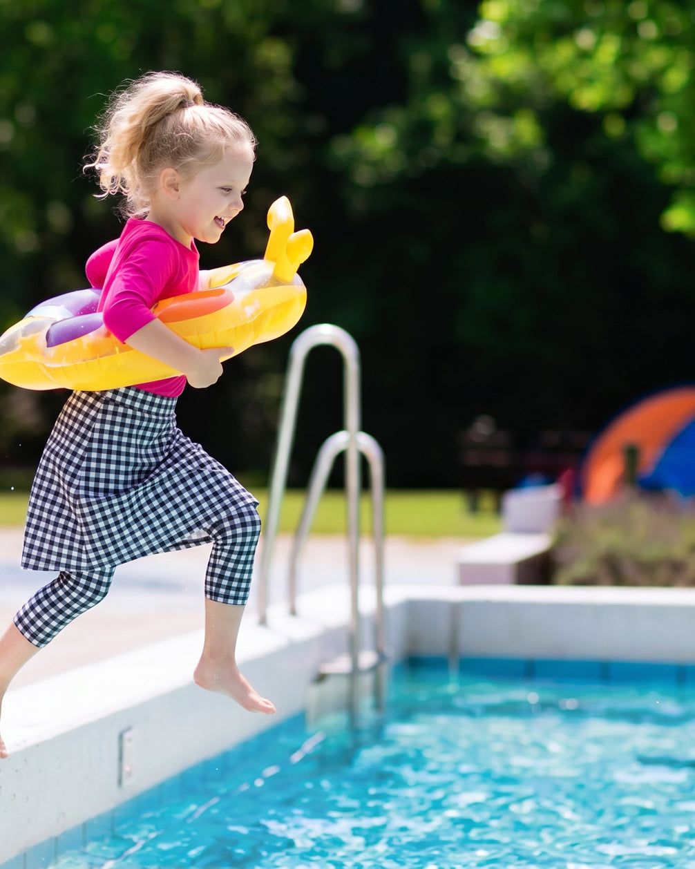 Child with a yellow inflatable ring jumping into a pool