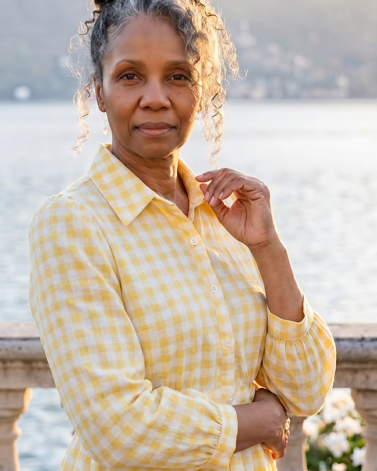 A picture of a women wearing a yellow and white gingham shirt dress with side ties.