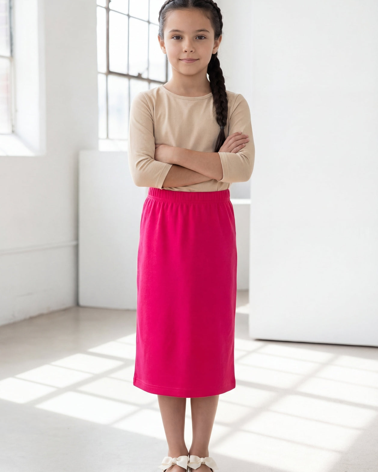 Model wearing the Nuggles® Girls' Classic Midi Skirt in Hot Pink