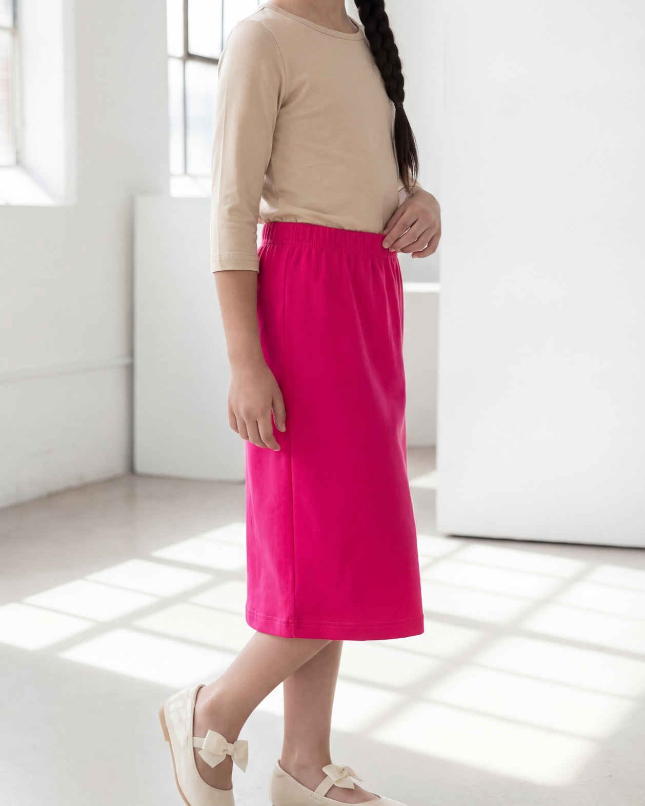 Model wearing the Nuggles® Girls' Classic Midi Skirt in Hot Pink