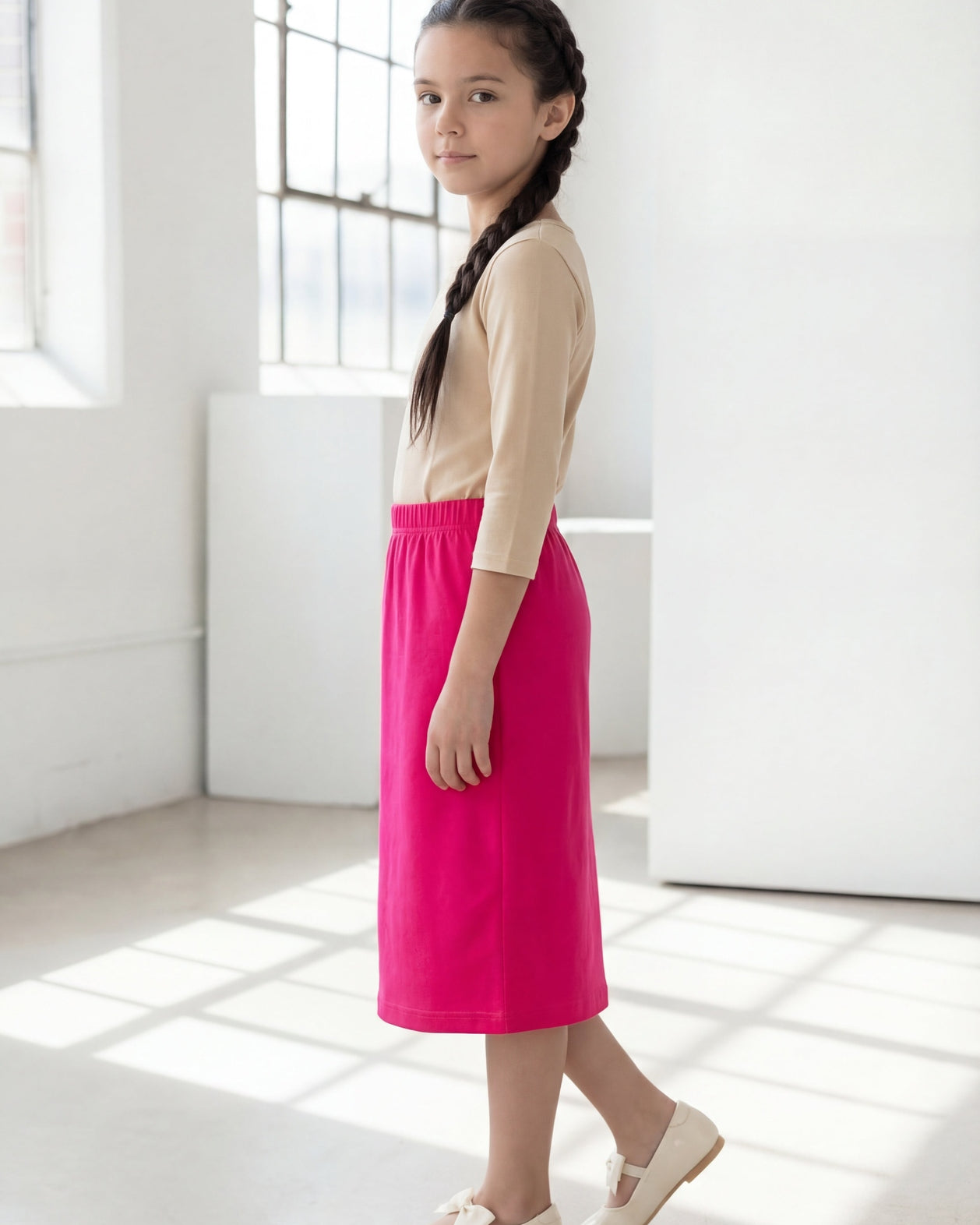 Model wearing the Nuggles® Girls' Classic Midi Skirt in Hot Pink