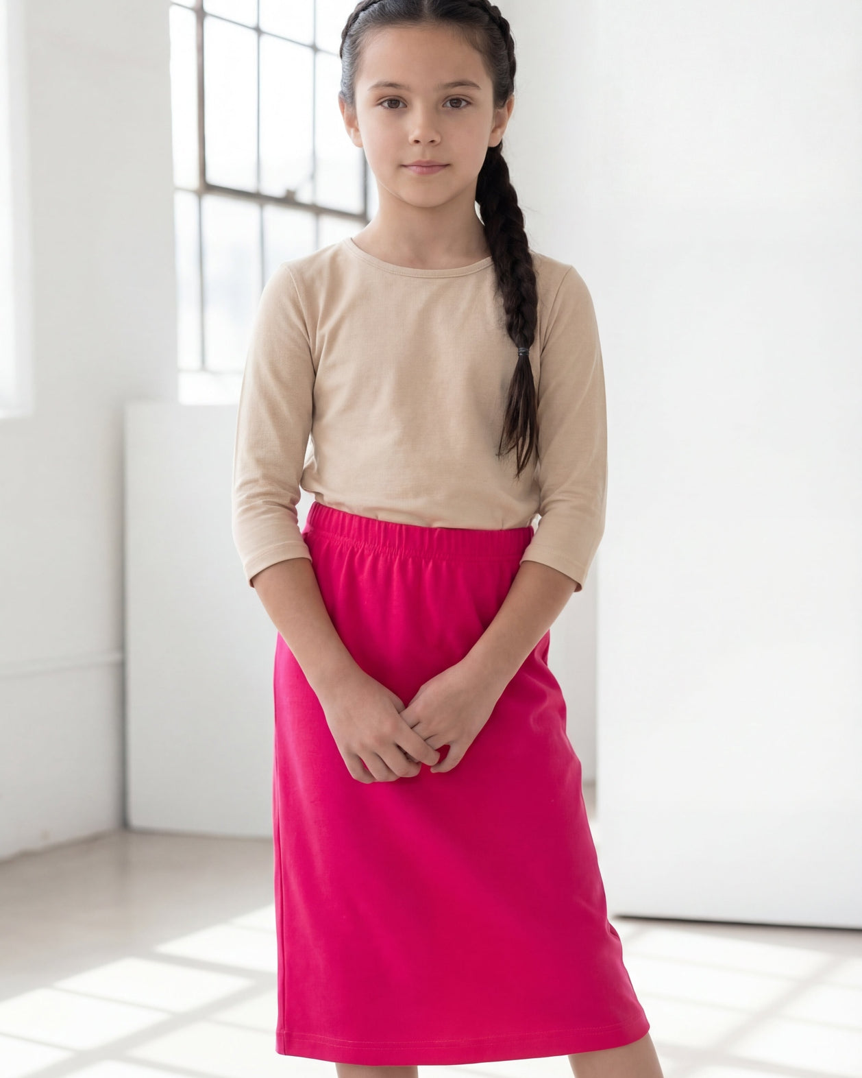 Model wearing the Nuggles® Girls' Classic Midi Skirt in Hot Pink