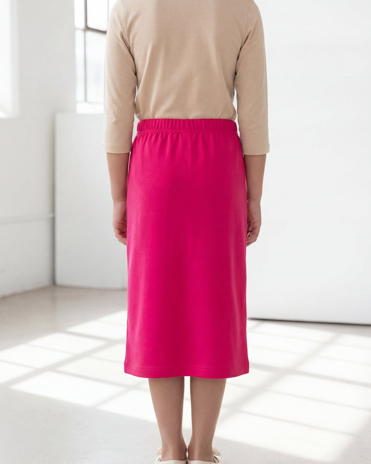 Model wearing the Nuggles® Girls' Classic Midi Skirt in Hot Pink