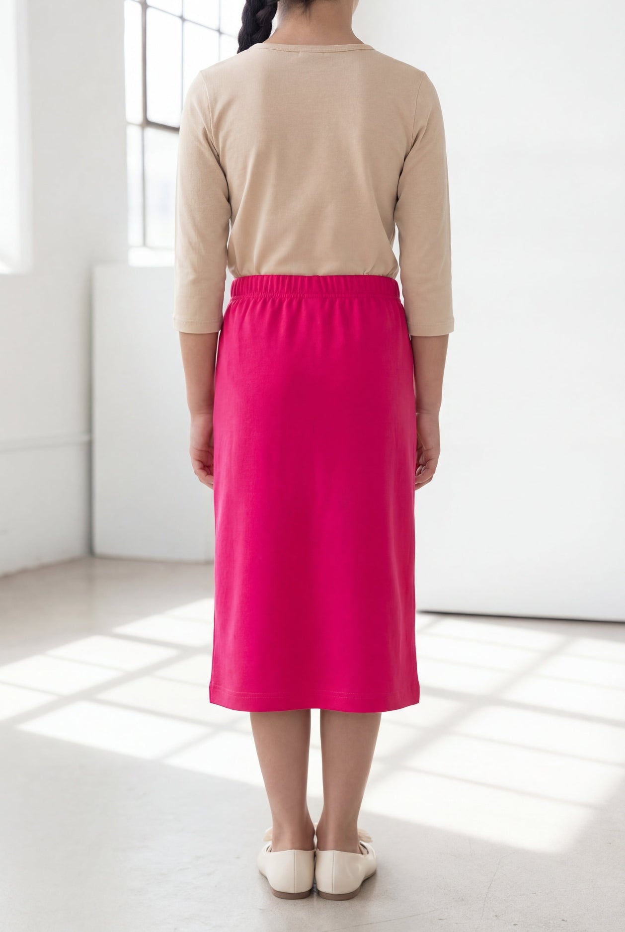 Model wearing the Nuggles® Girls' Classic Midi Skirt in Hot Pink