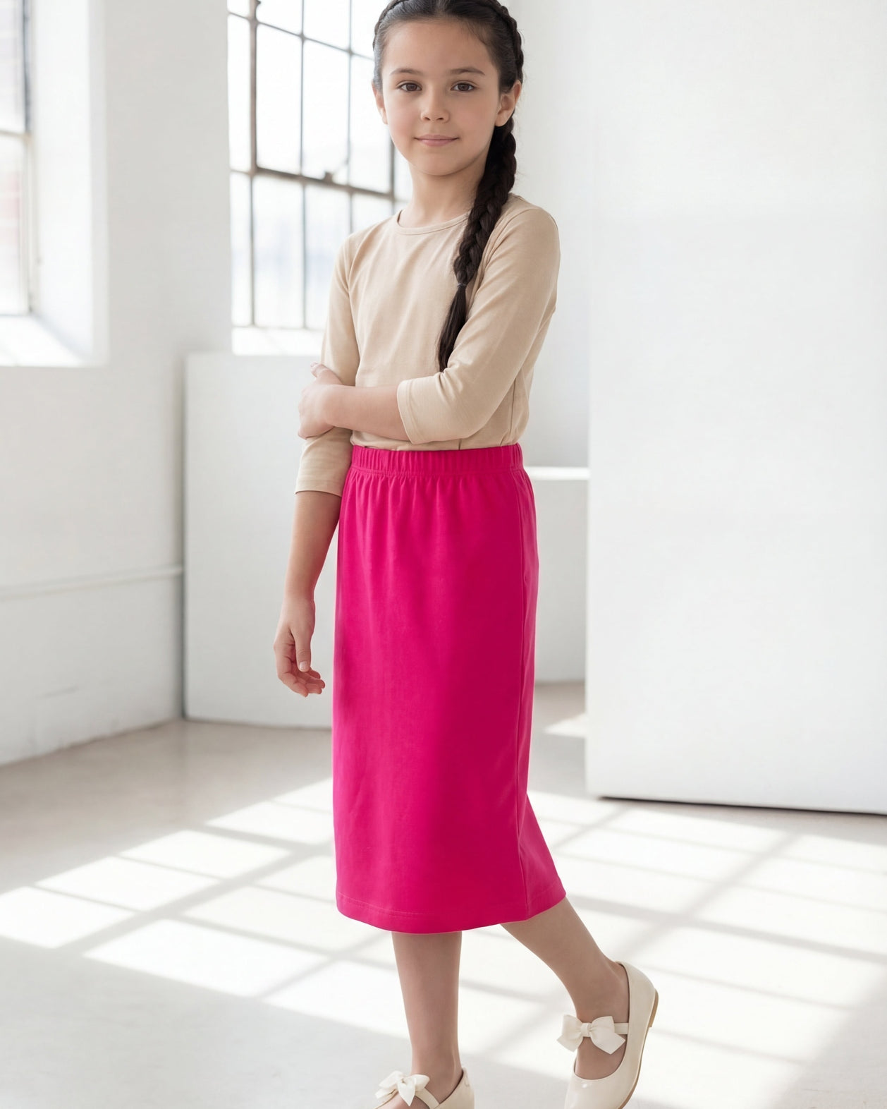 Model wearing the Nuggles® Girls' Classic Midi Skirt in Hot Pink