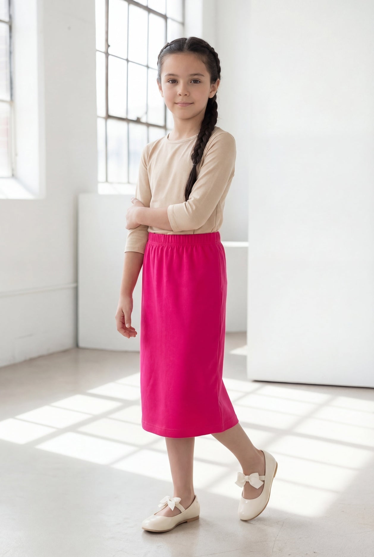 Model wearing the Nuggles® Girls' Classic Midi Skirt in Hot Pink