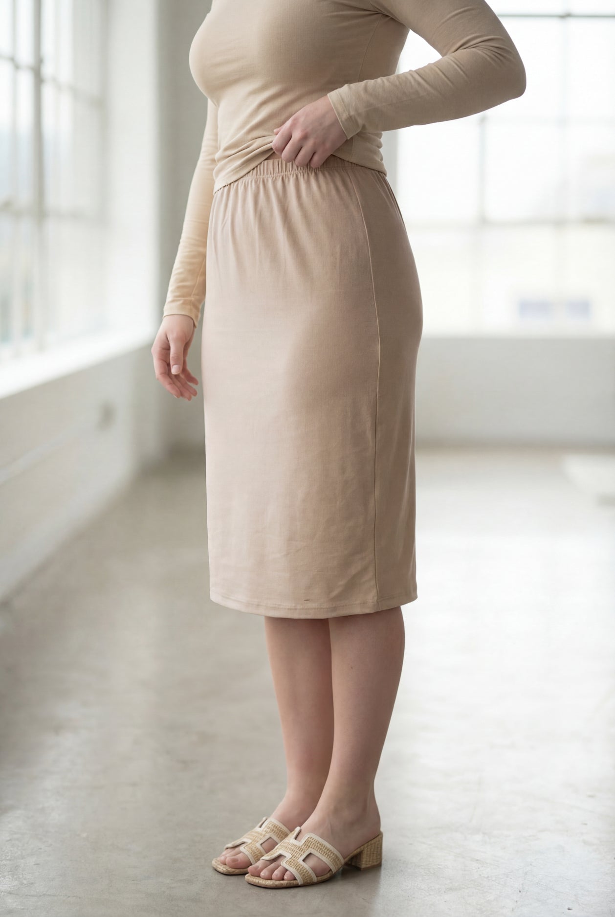 Women wearing a khaki classic 27" midi length skirt with a beige shirt in a sunlight loft.
