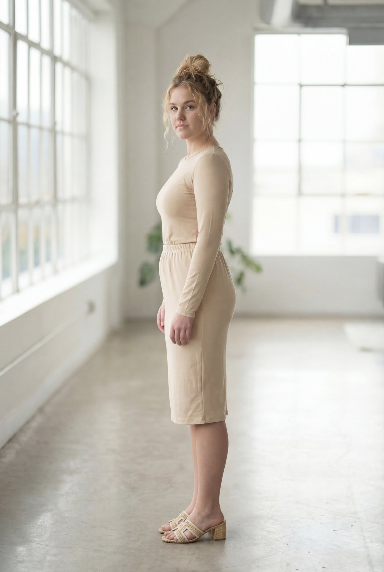Women wearing a nude classic 27" midi length skirt with a beige shirt in a sunlight loft.