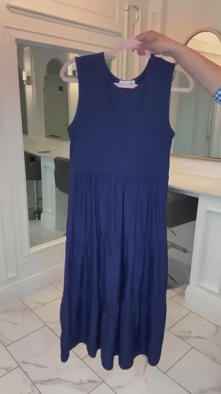 Model wearing the Hannah Layering Dress by Nuggles®, showcasing modest sleeveless midi style with tiered skirt and stretch waistband, layered over a mesh top for styling versatility.