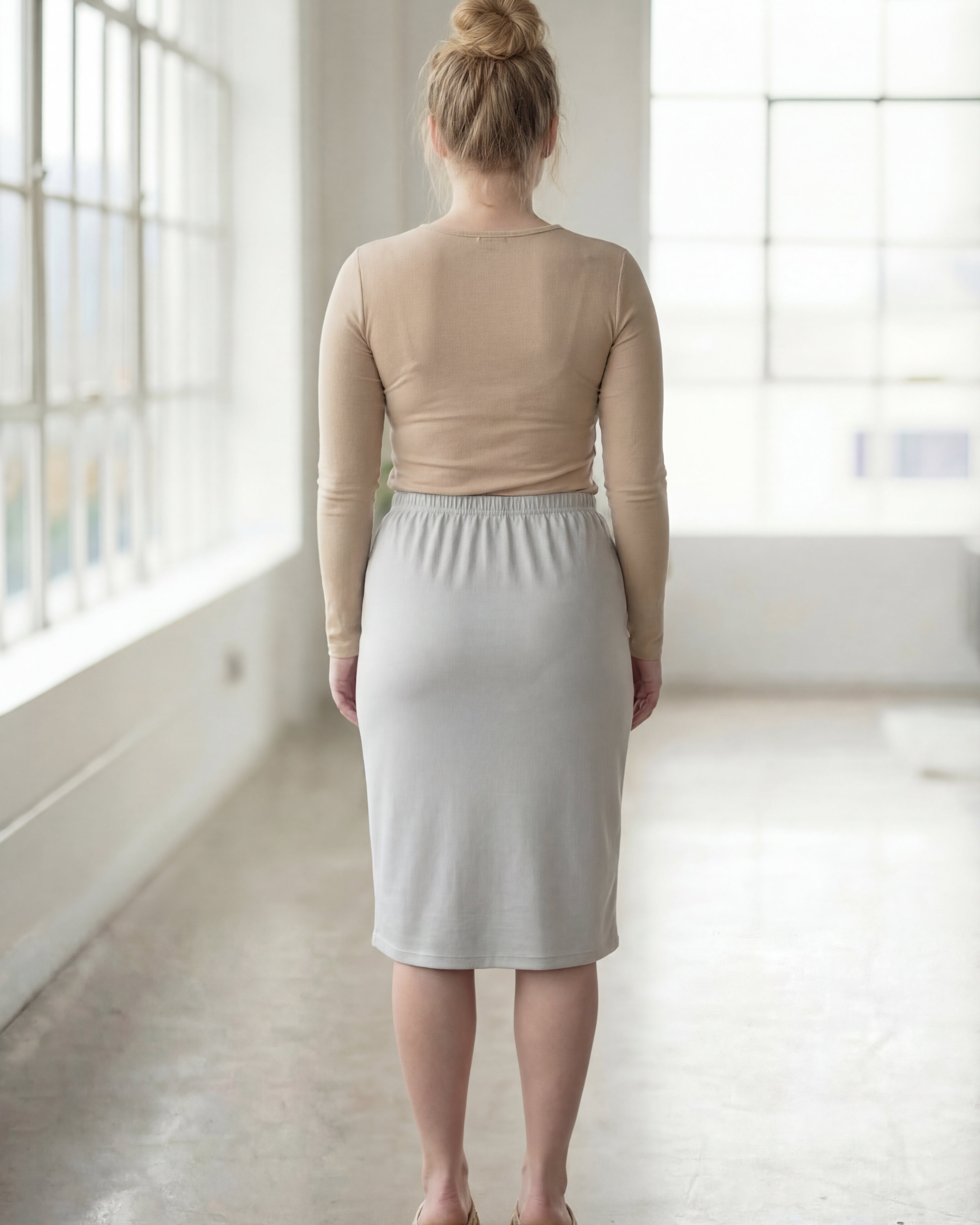 Women wearing a silver classic 27" midi length skirt with a beige shirt in a sunlight loft.