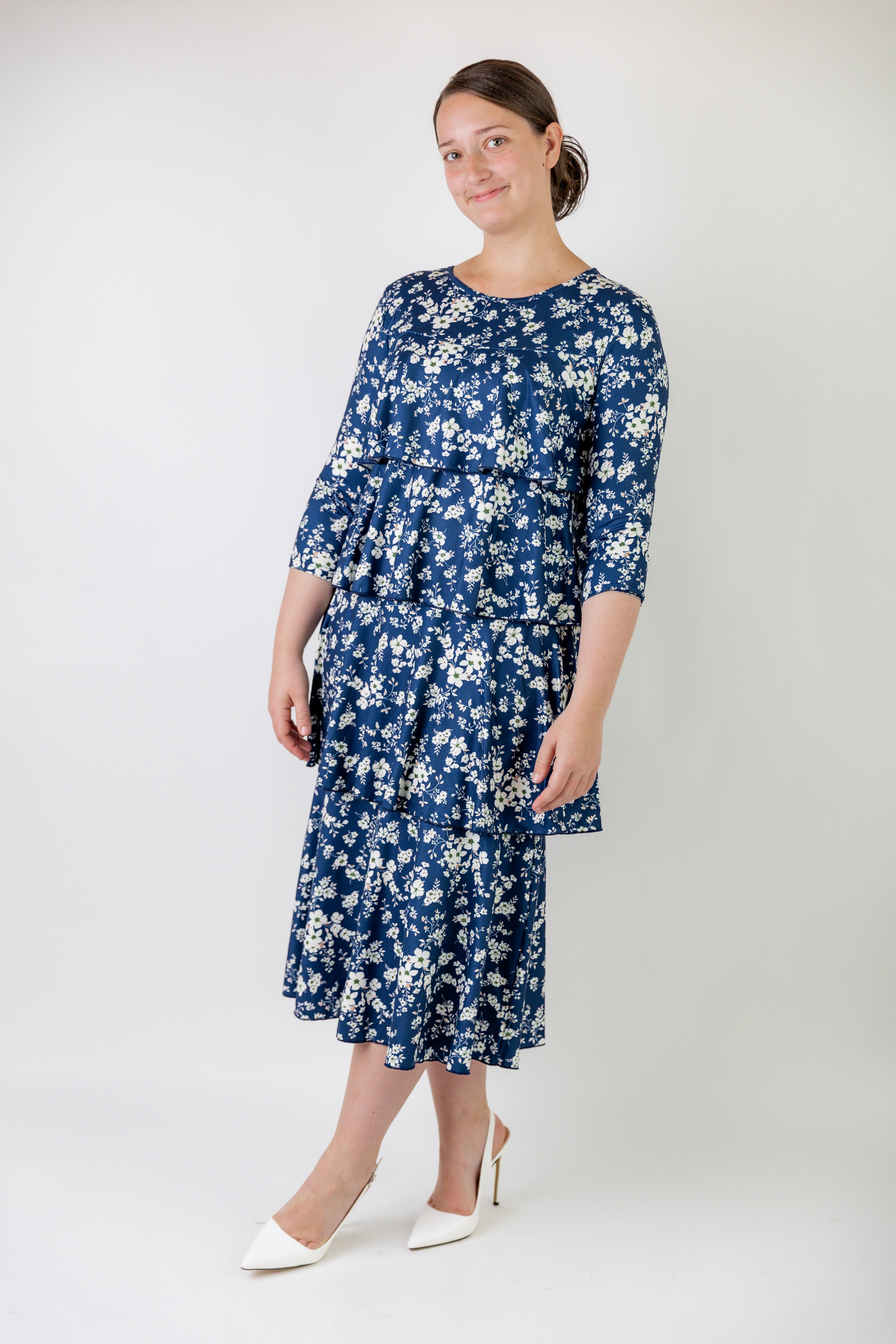 A woman wearing a blue and white print, modest, midi length dress.