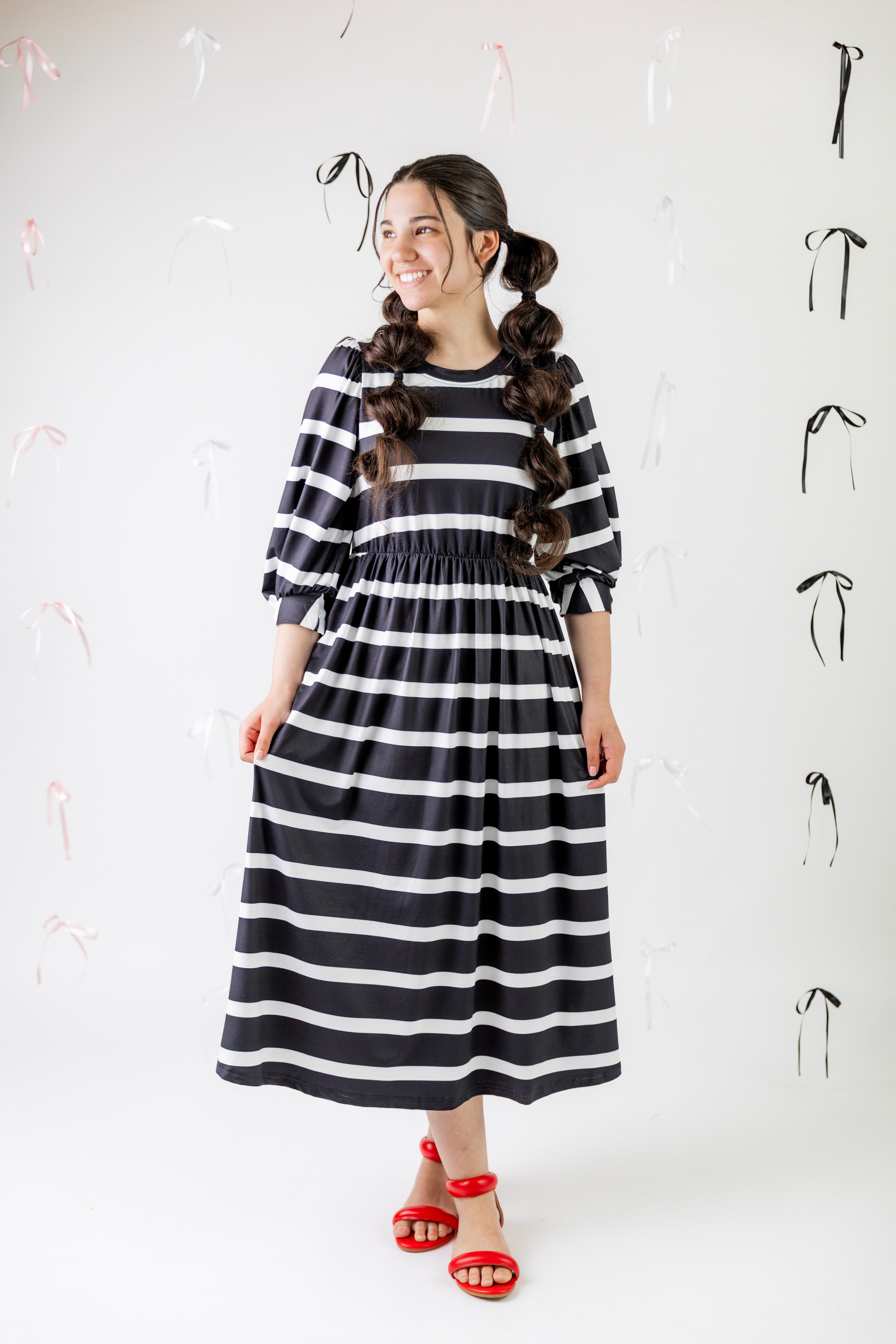 Women wearing a modest, midi length dress with 3/4 length sleeves in a fun black and white horizontal stripe print.