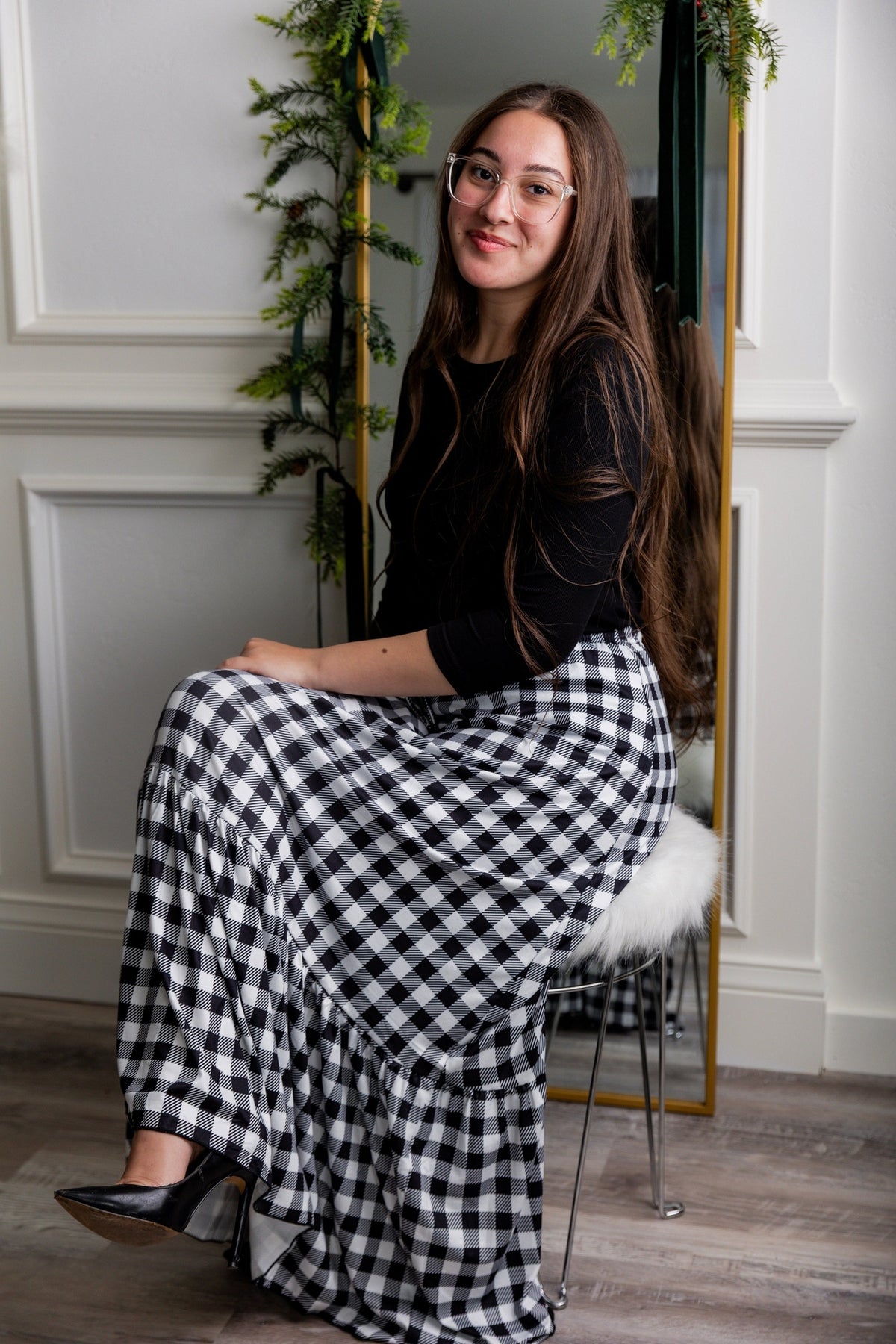 A women seated in front of a mirror wearing a black layering tee and the black and white plaid Sage maxi skirt.