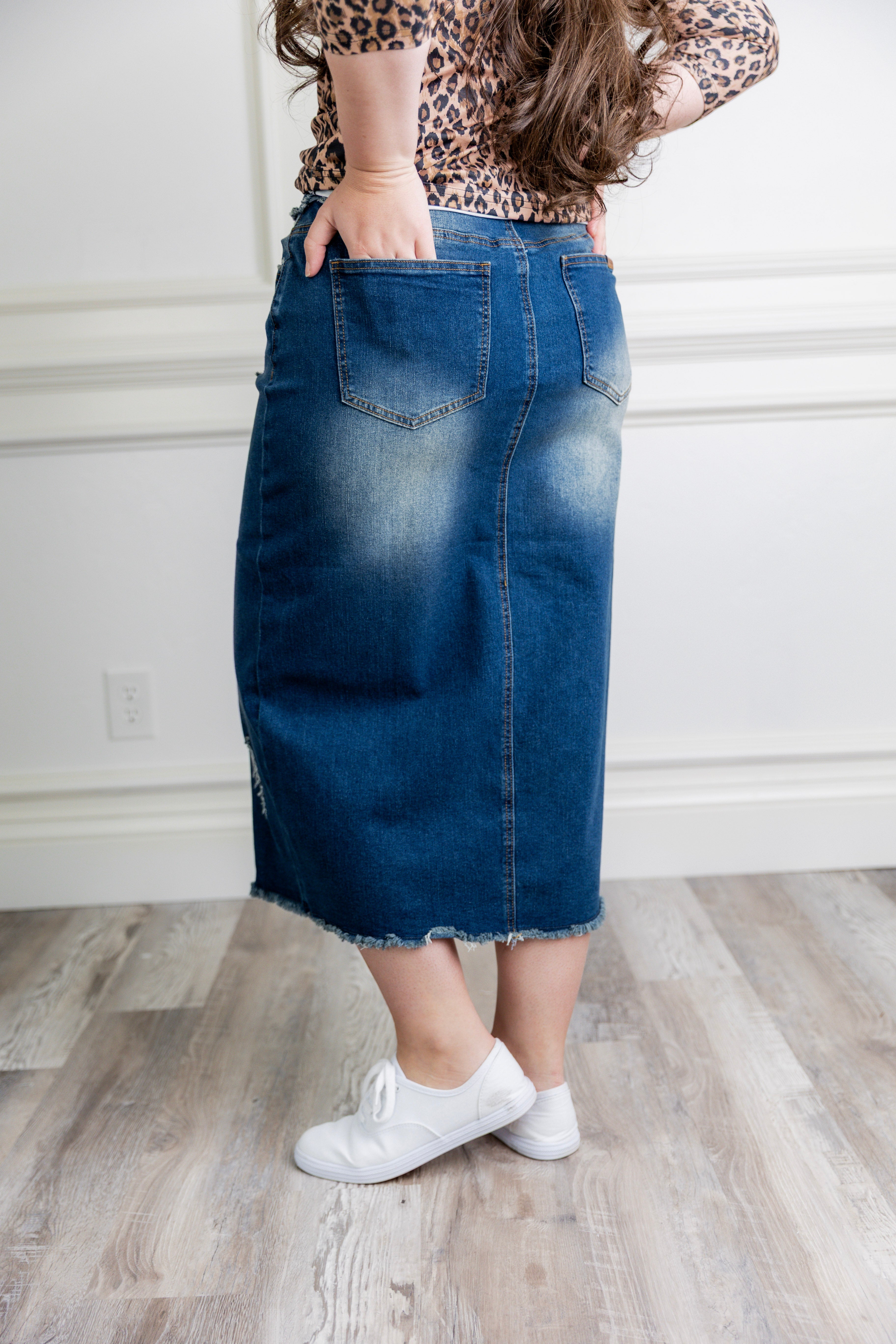 Woman wearing a modest, midi length, stretch denim skirt with a wide elastic waistband.