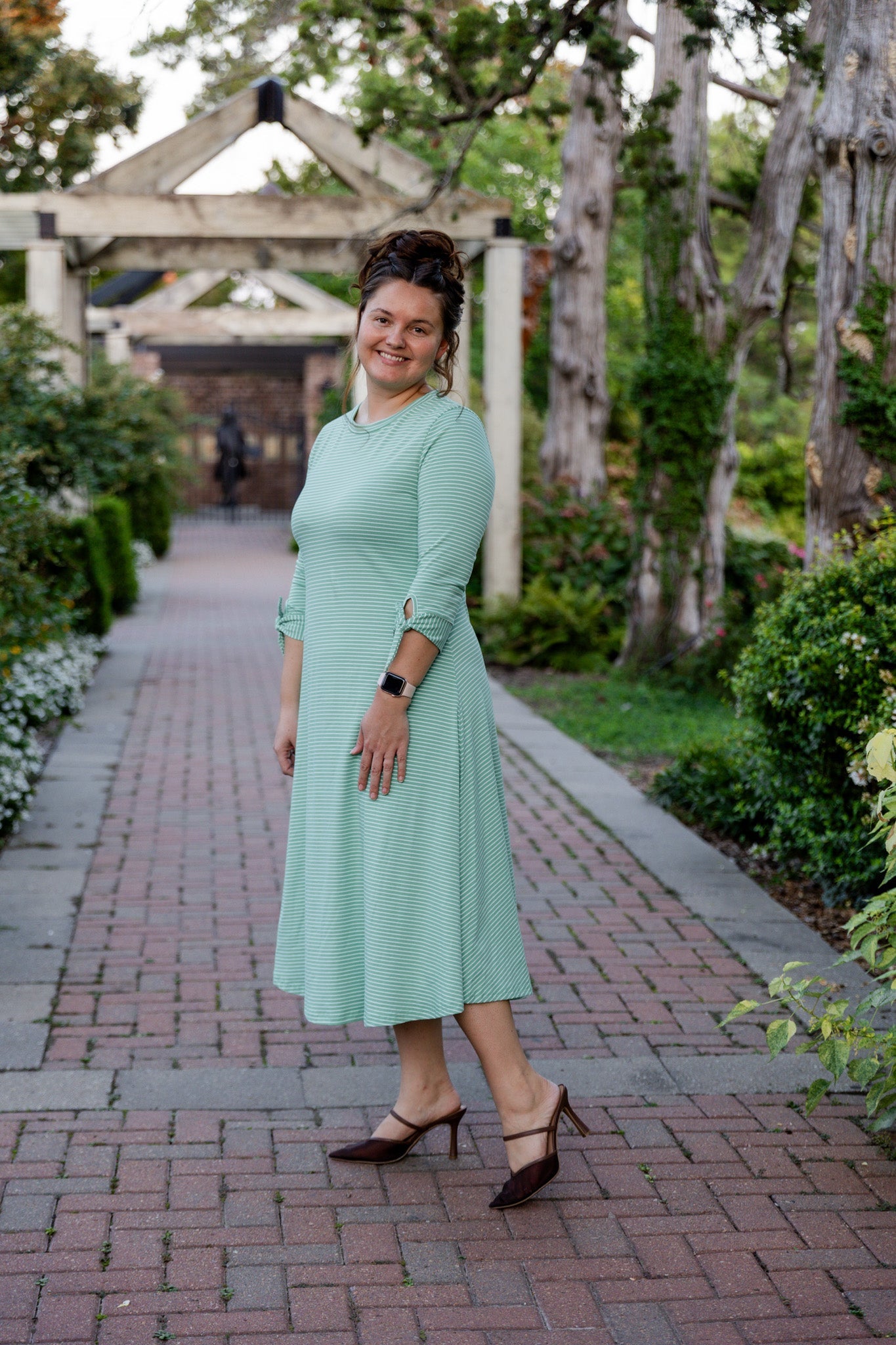 Woman wearing a modest, midi dress that is also available in plus sizes and is maternity friendly. The dress features blue stripes as well as a fun leopard print. 
