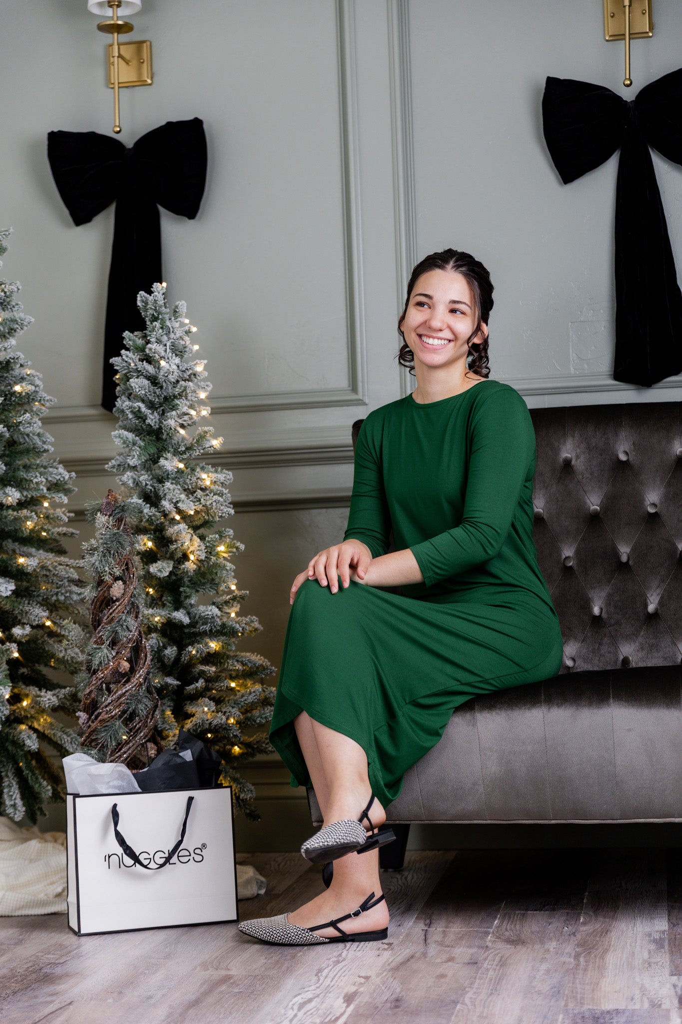 A women wearing a green Nuggles® Layering Dress with Christmas Trees in the background.