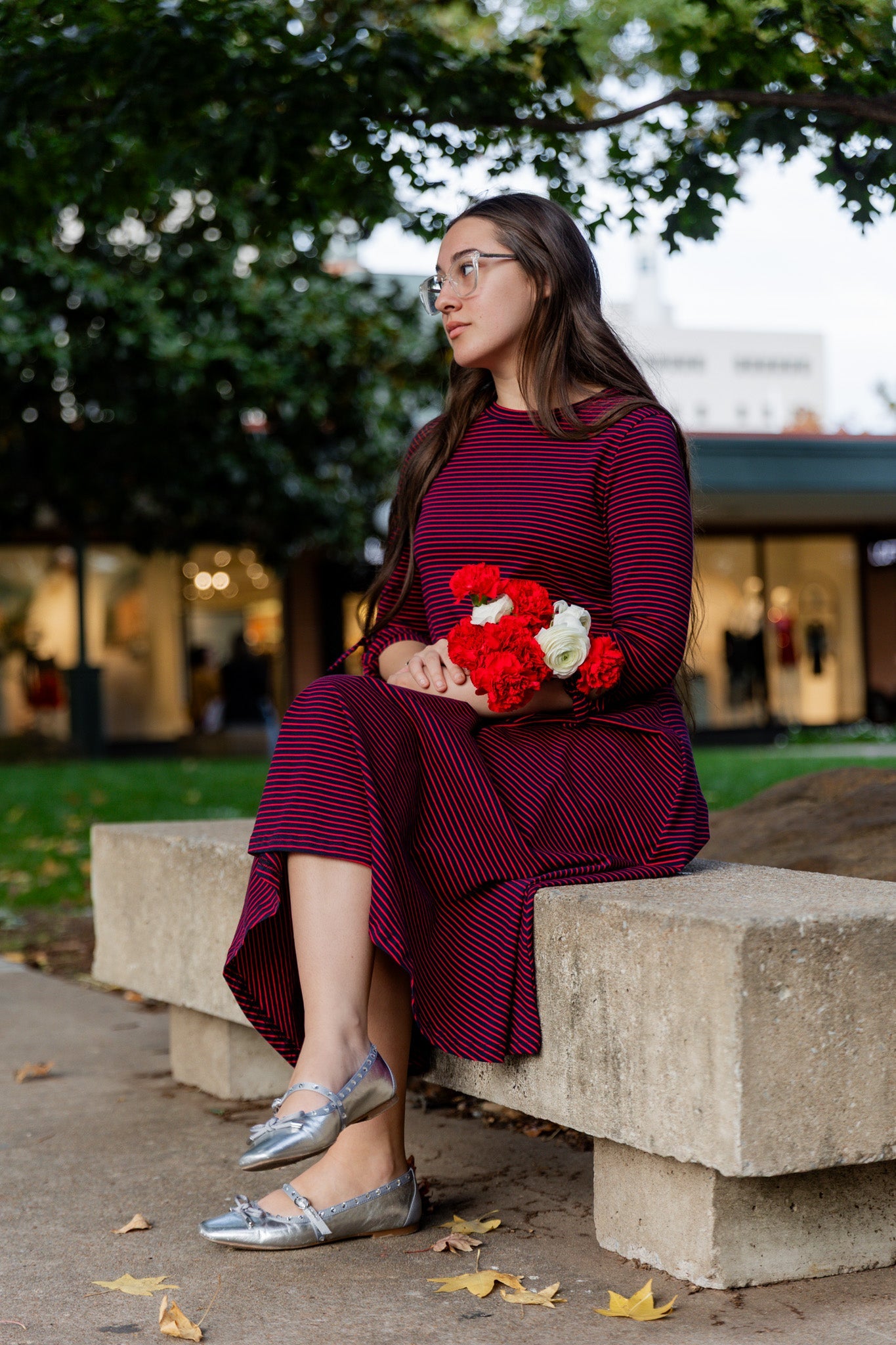 A women wearing a Nuggles® red and blue striped Gracie dress holding flowers.