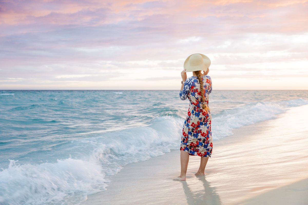A women wearing one of the sport swim dresses in a strawberry print with 3/4 sleeves and a midi length.