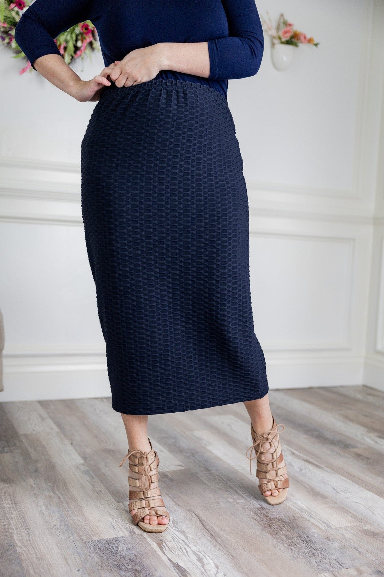 A women wearing a modest, midi length blue skirt that is available in plus sizes. 
