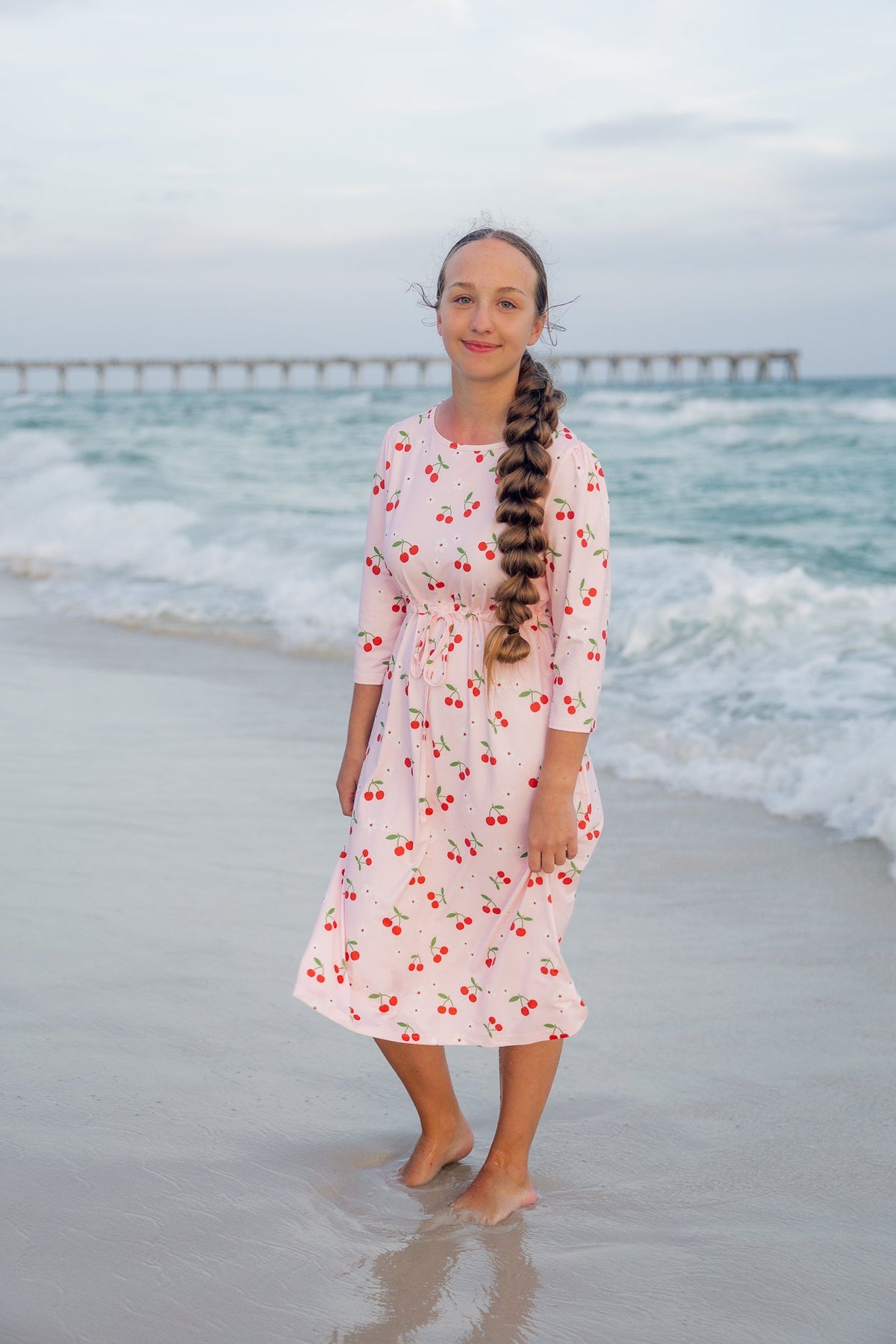 A women wearing the Nola Release dress in size small. Featuring an adjustable waist tie and midi length.