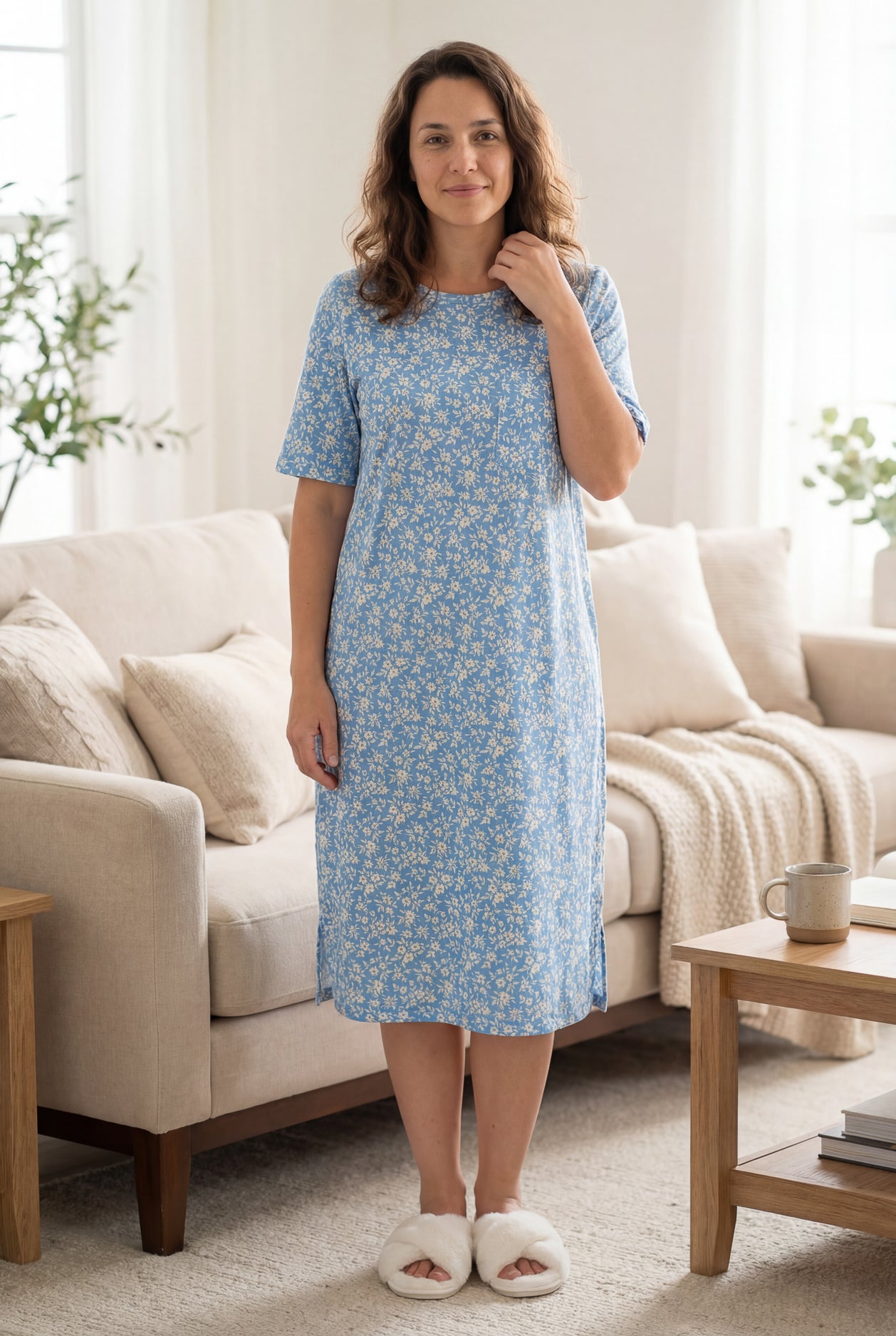 Woman wearing a blue floral dress standing in a living room.