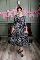 Model wearing Nuggles® Hazel Dress in Zebra Swirl black and white print with bow sleeves.