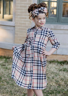 Model wearing the Nuggles® Girls' Rachel Dress and matching Headband in Sand Plaid