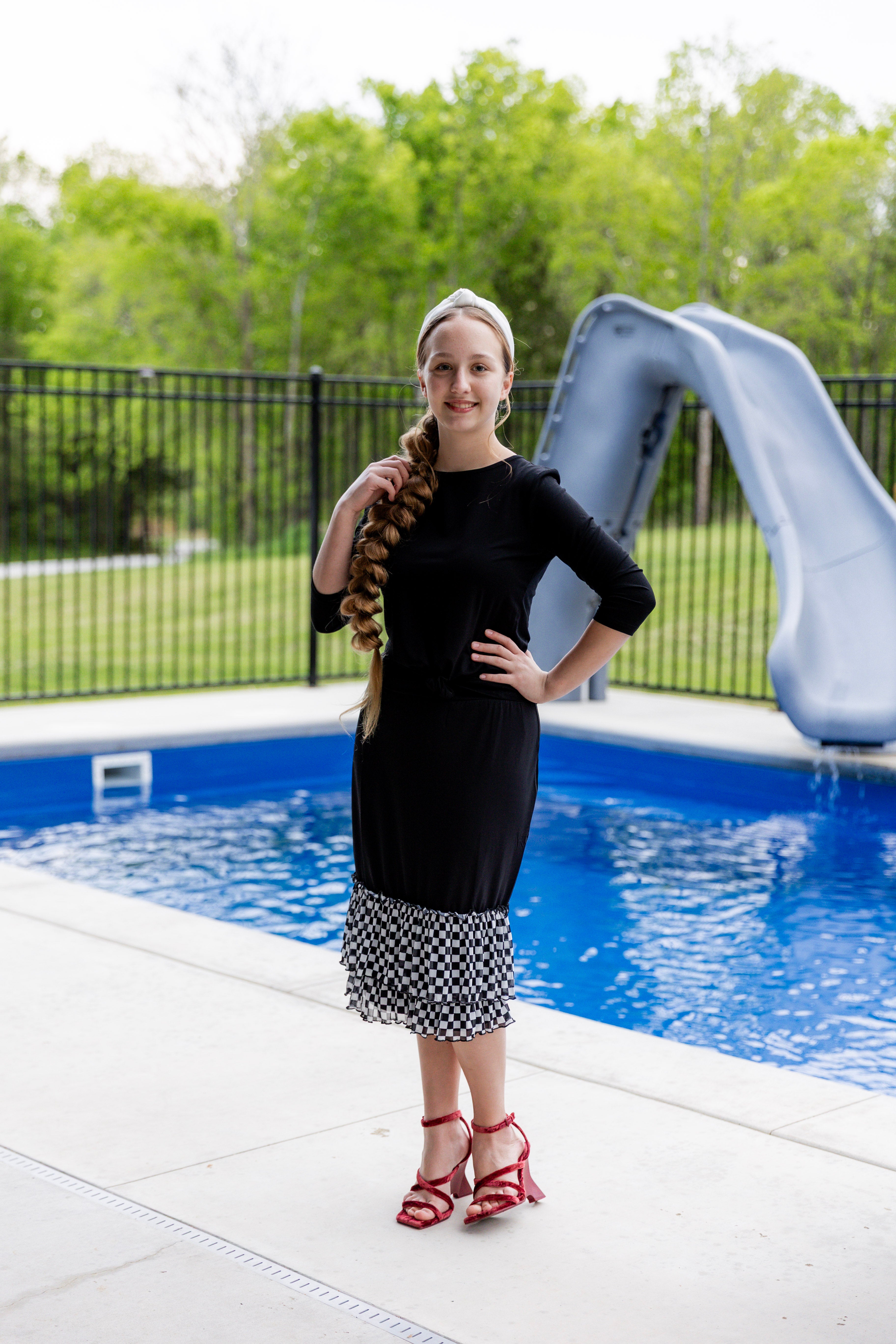 Woman wearing a black 27" slip skirt with black-and-white checkered ruffle trim.