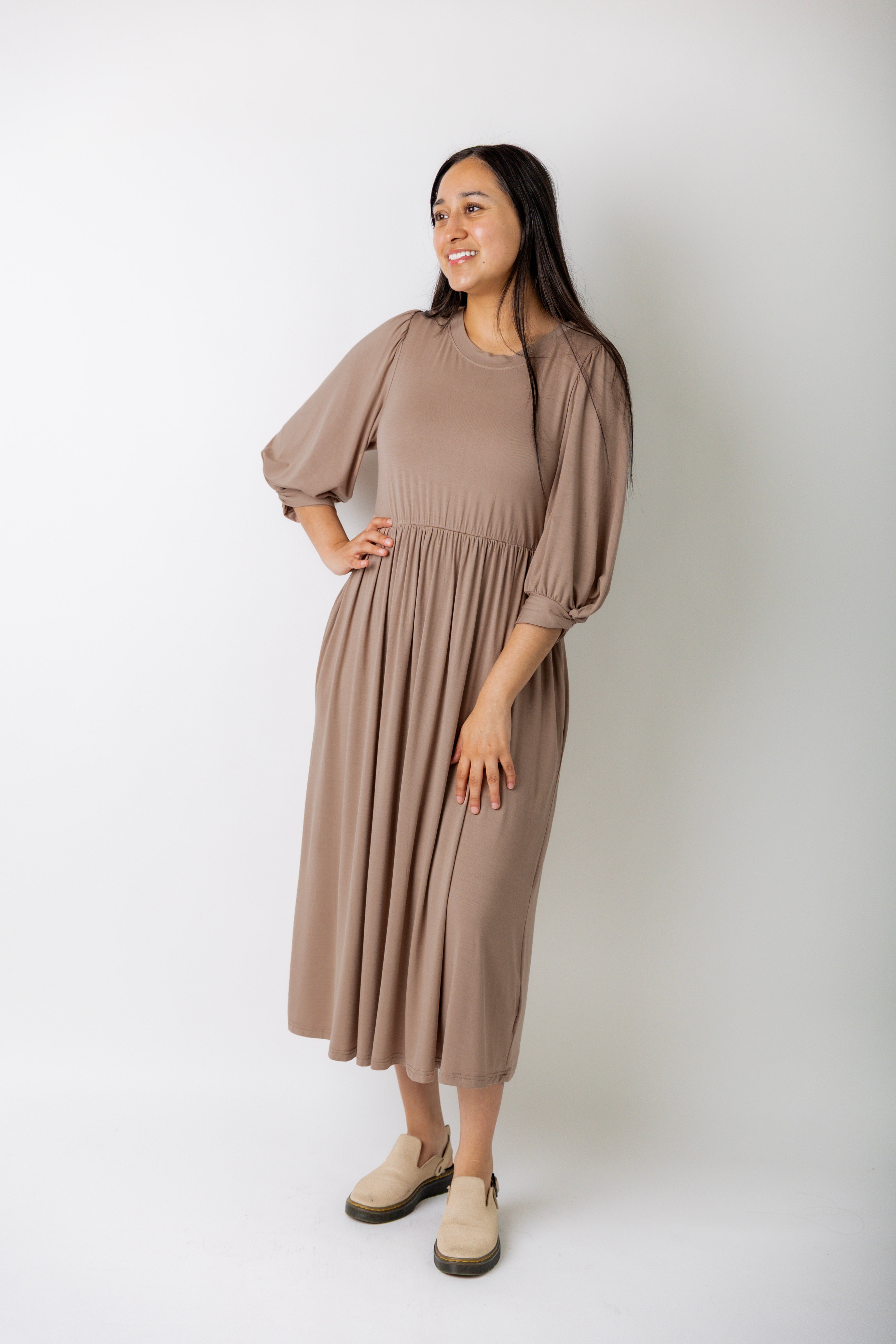 Modest Willow Solid Colors Dress by Nuggles® featuring a gathered waist, balloon sleeves, and side pockets; shown in various solid colors and angles for a stylish, comfortable everyday look.