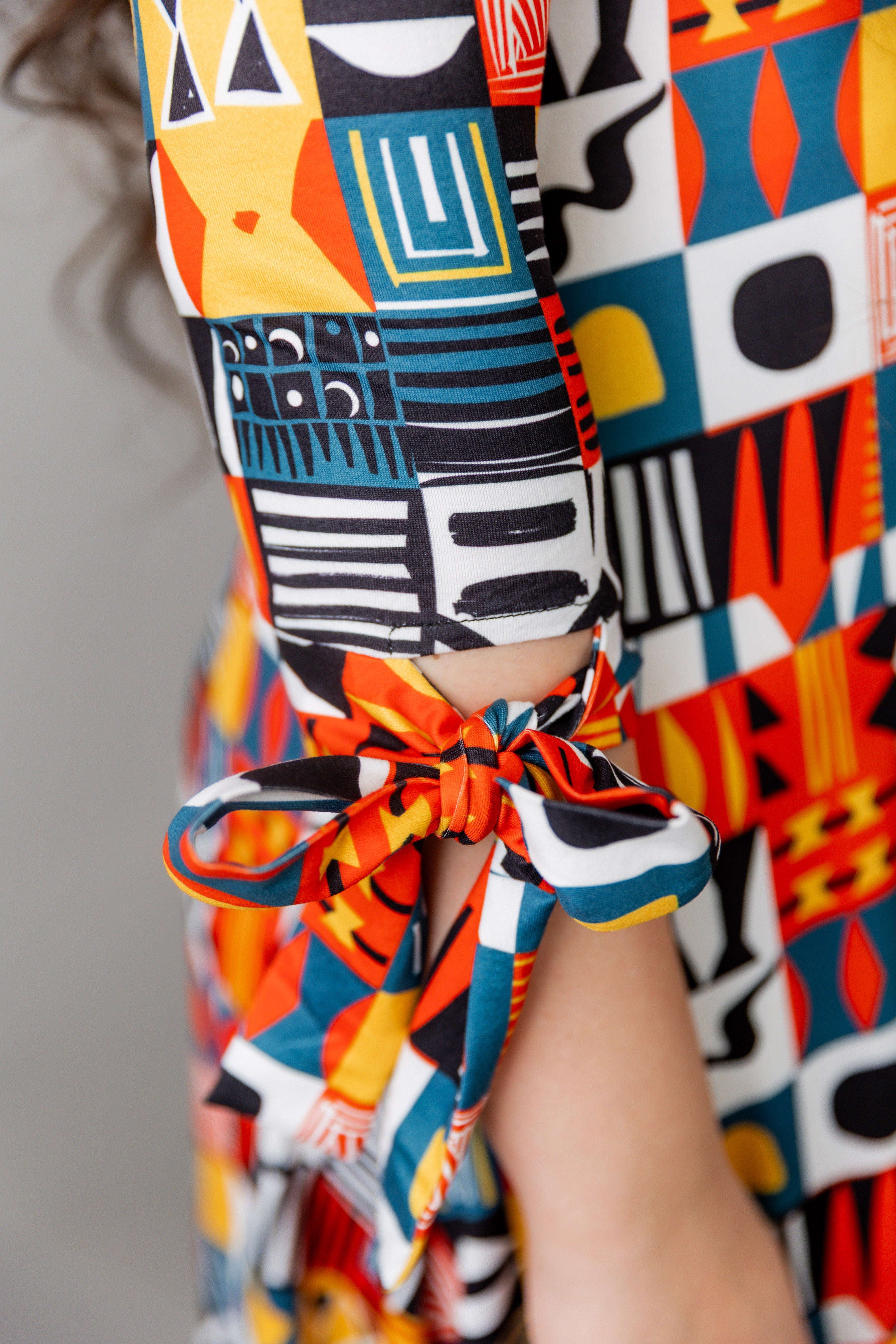 Model wearing Nuggles® Hazel Dress in Playful Patchwork print with bow-tie sleeves