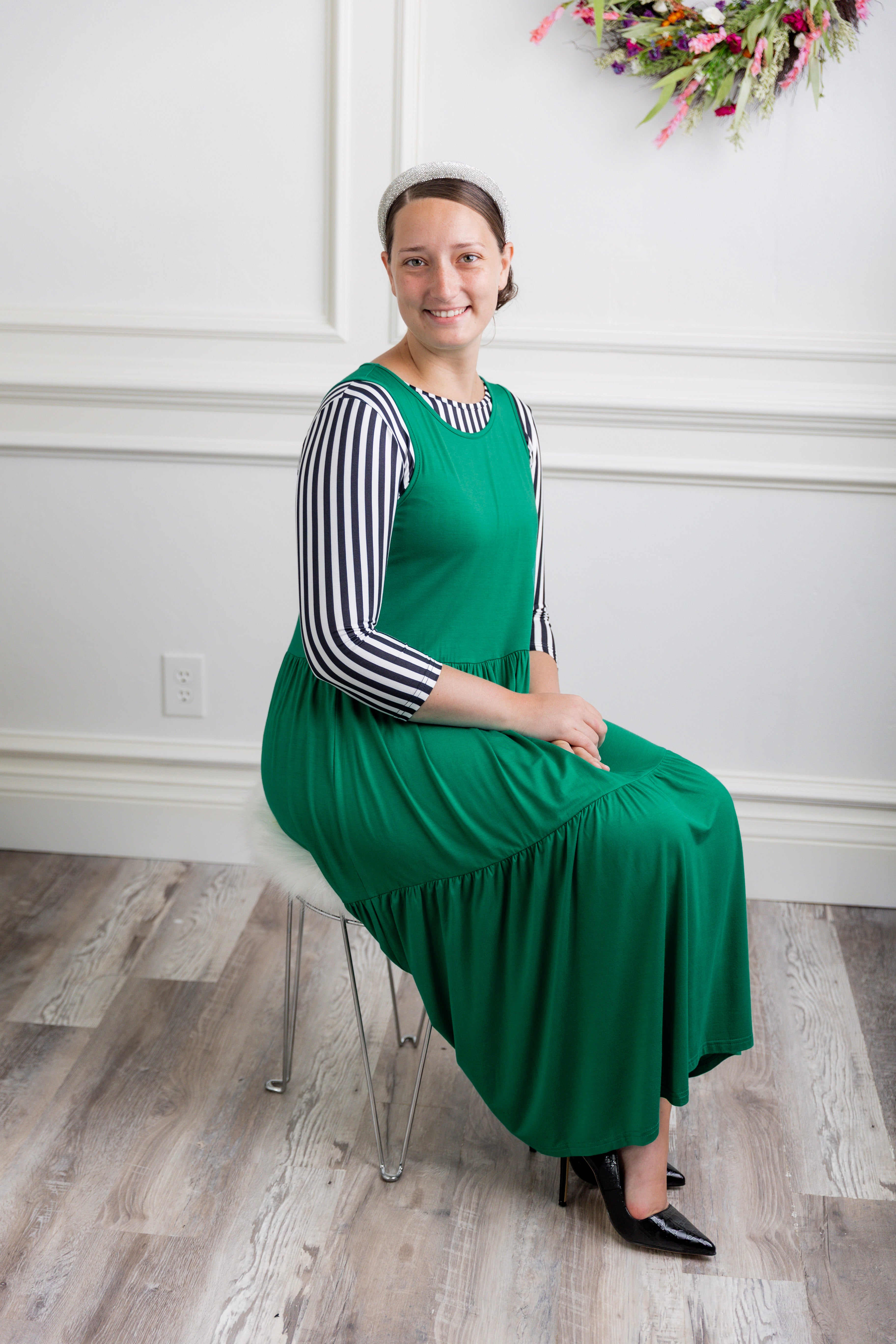 model wearing a shamrock tiered midi dress over a black and white striped sleeve top.