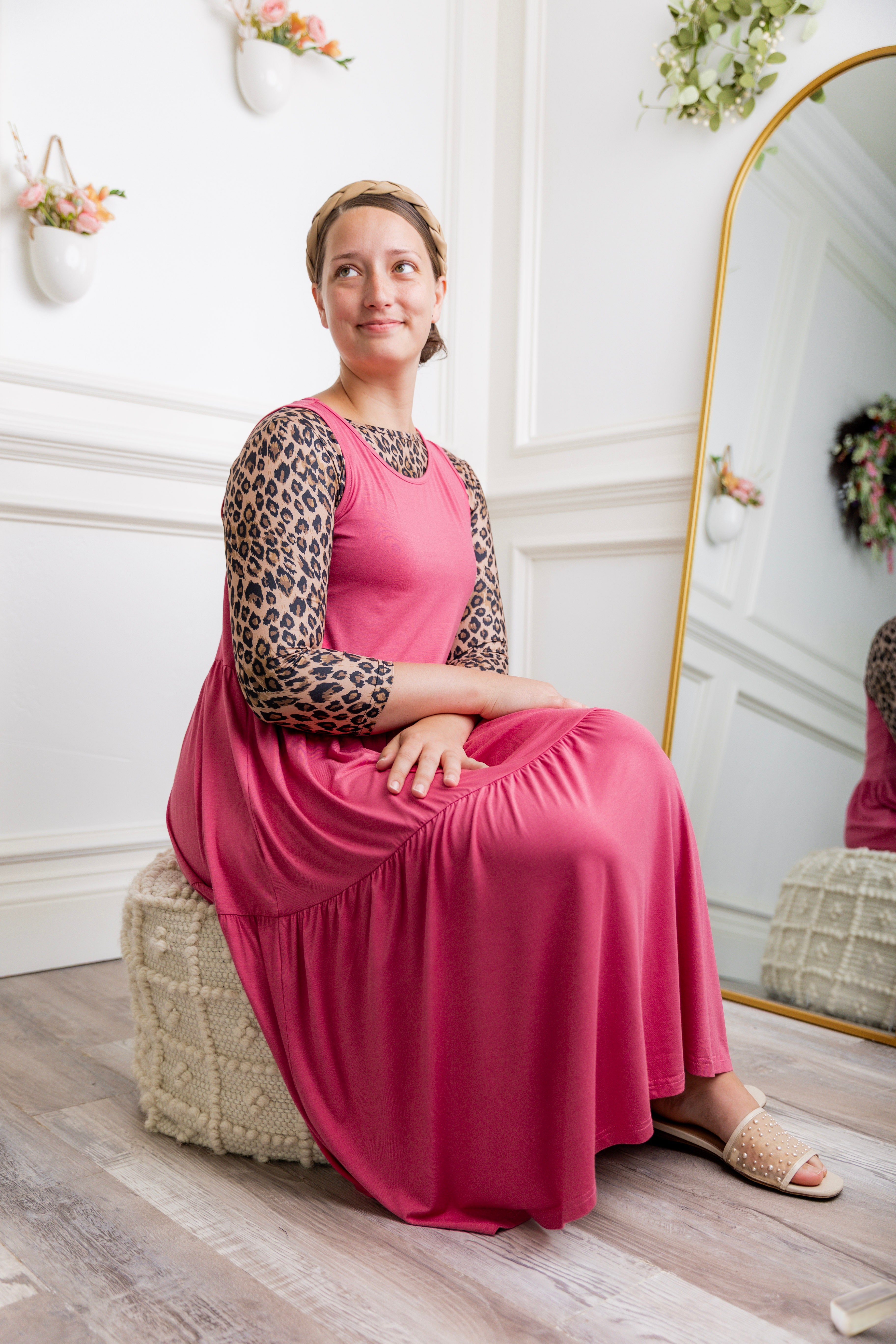 model modeling a pink tiered midi dress over a leopard print sleeve top, styled with nude studded sandals and a braided headband.