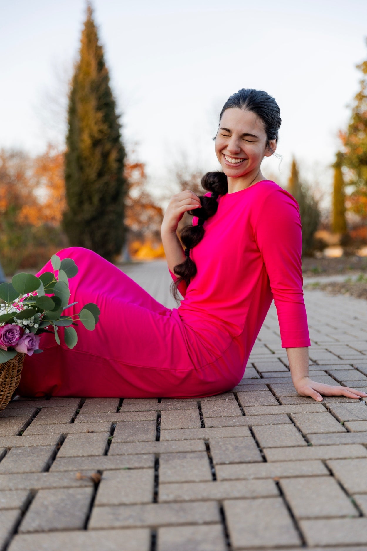 Woman wearing a bright pink dress in a minimalistic room with large windows.
