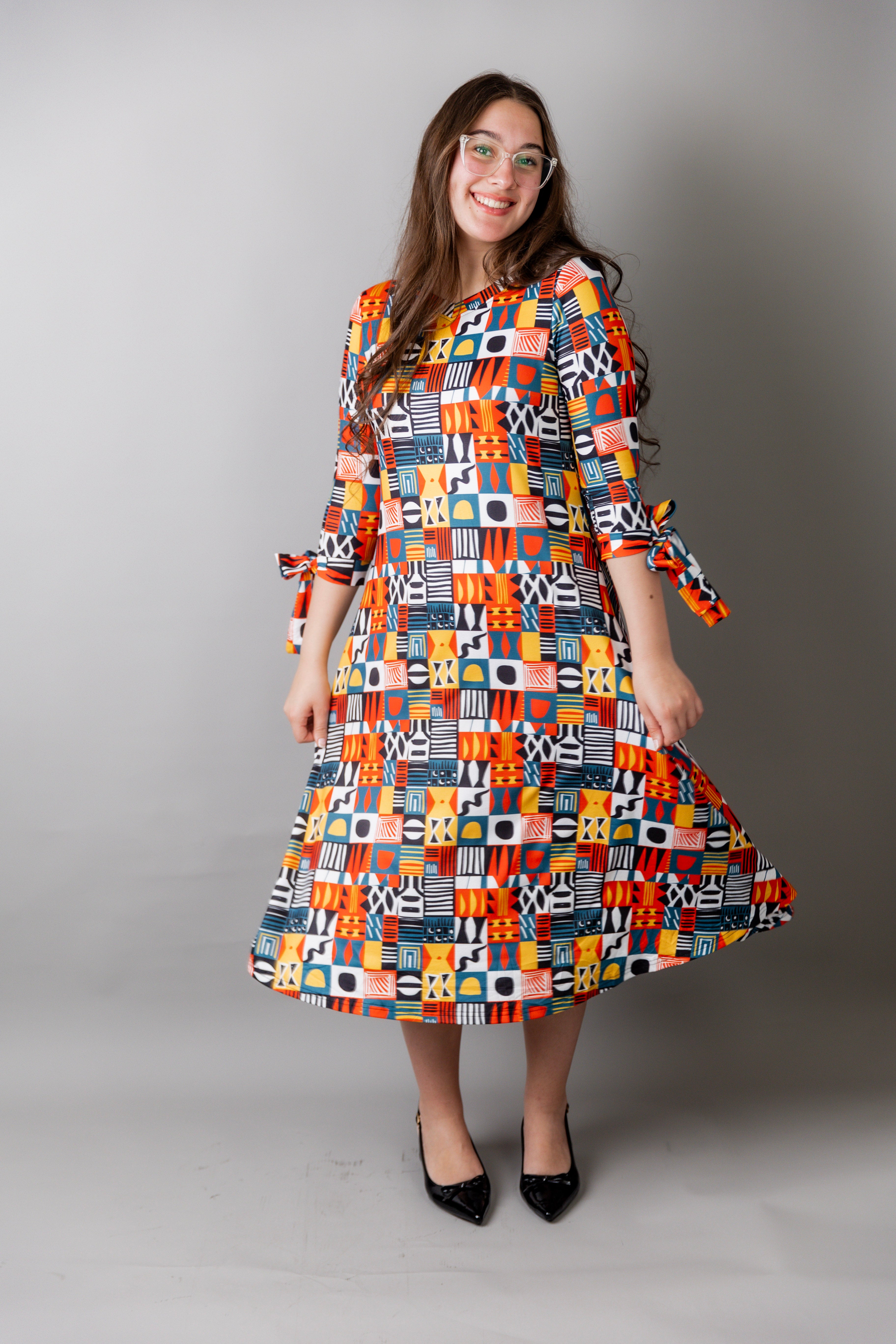 Model wearing Nuggles® Hazel Dress in Playful Patchwork print with bow-tie sleeves