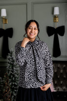 Model wearing Nuggles® Felicity top with large bow tie neckline, modest women's blouse.