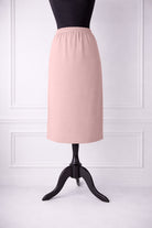 rose skirt on a mannequin against a white paneled wall.