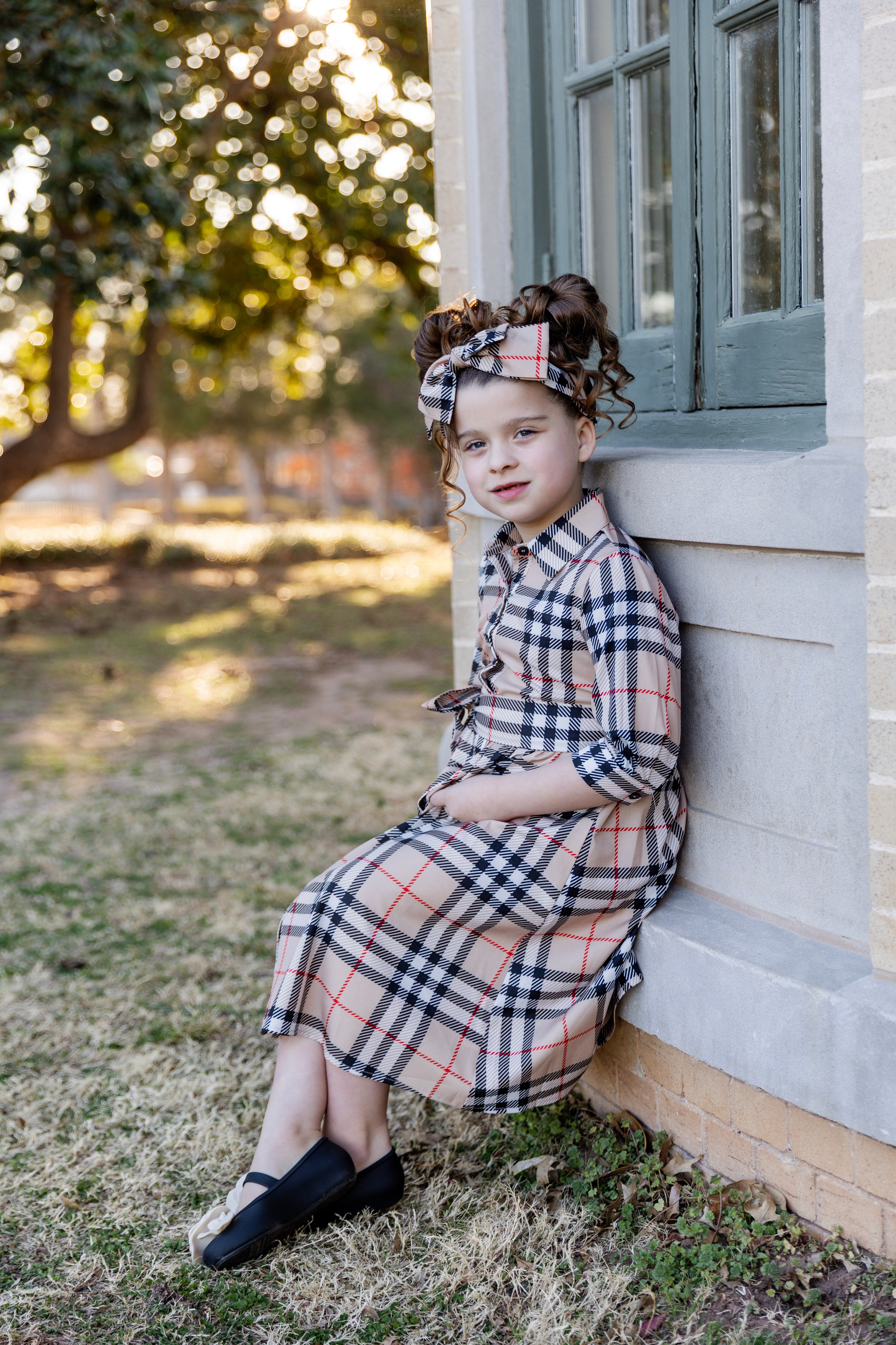 Model wearing the Nuggles® Girls' Rachel Dress in Sand Plaid