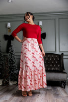 Model wearing the Nuggles® Sage Skirt in pink with red bow print, showcasing a tiered ruffle hem and soft, stretchy waistband.