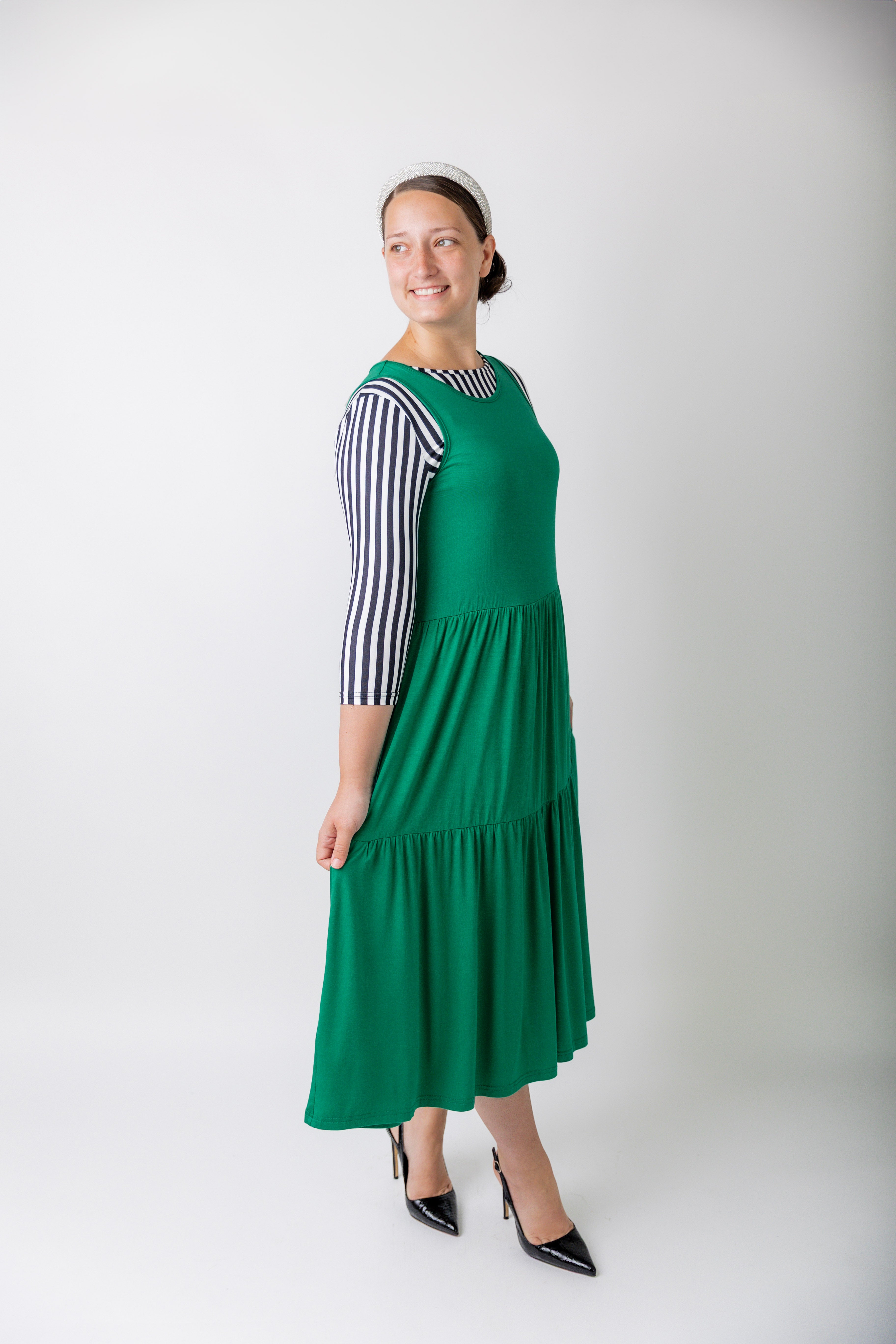 model wearing a shamrock tiered midi dress over a black and white striped sleeve top.