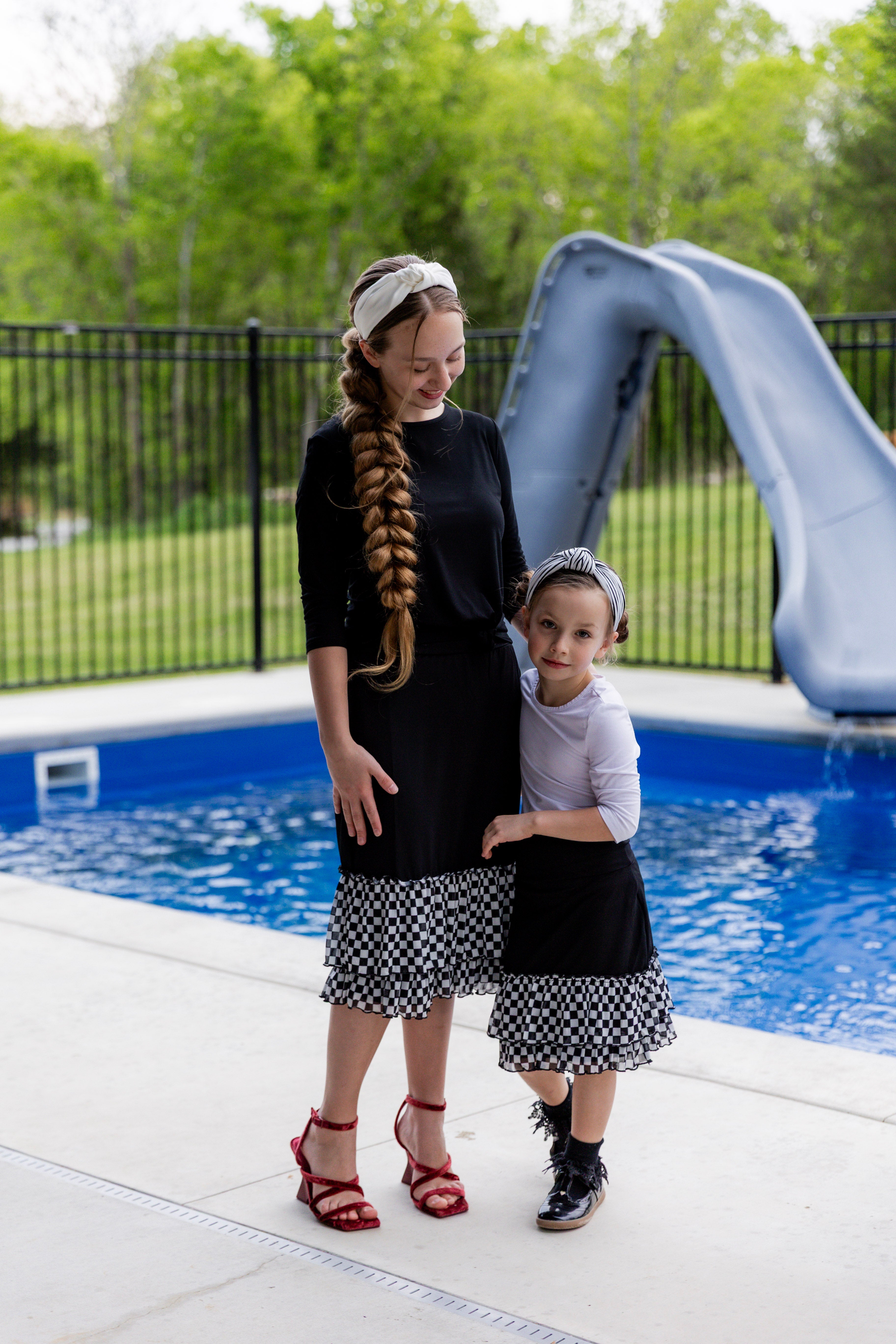 Woman wearing a black 27" slip skirt with black-and-white checkered ruffle trim.