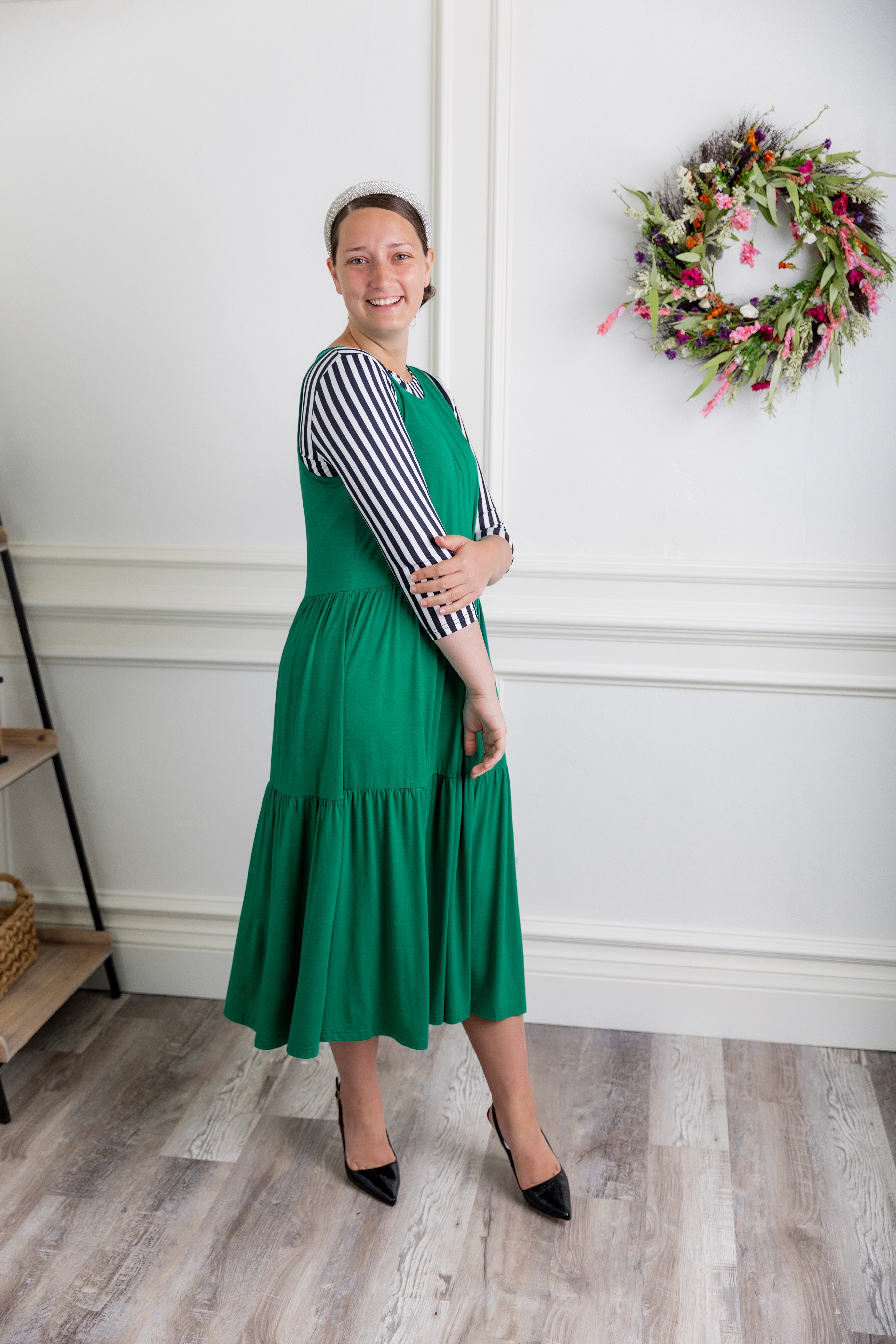 model wearing a shamrock tiered midi dress over a black and white striped sleeve top.