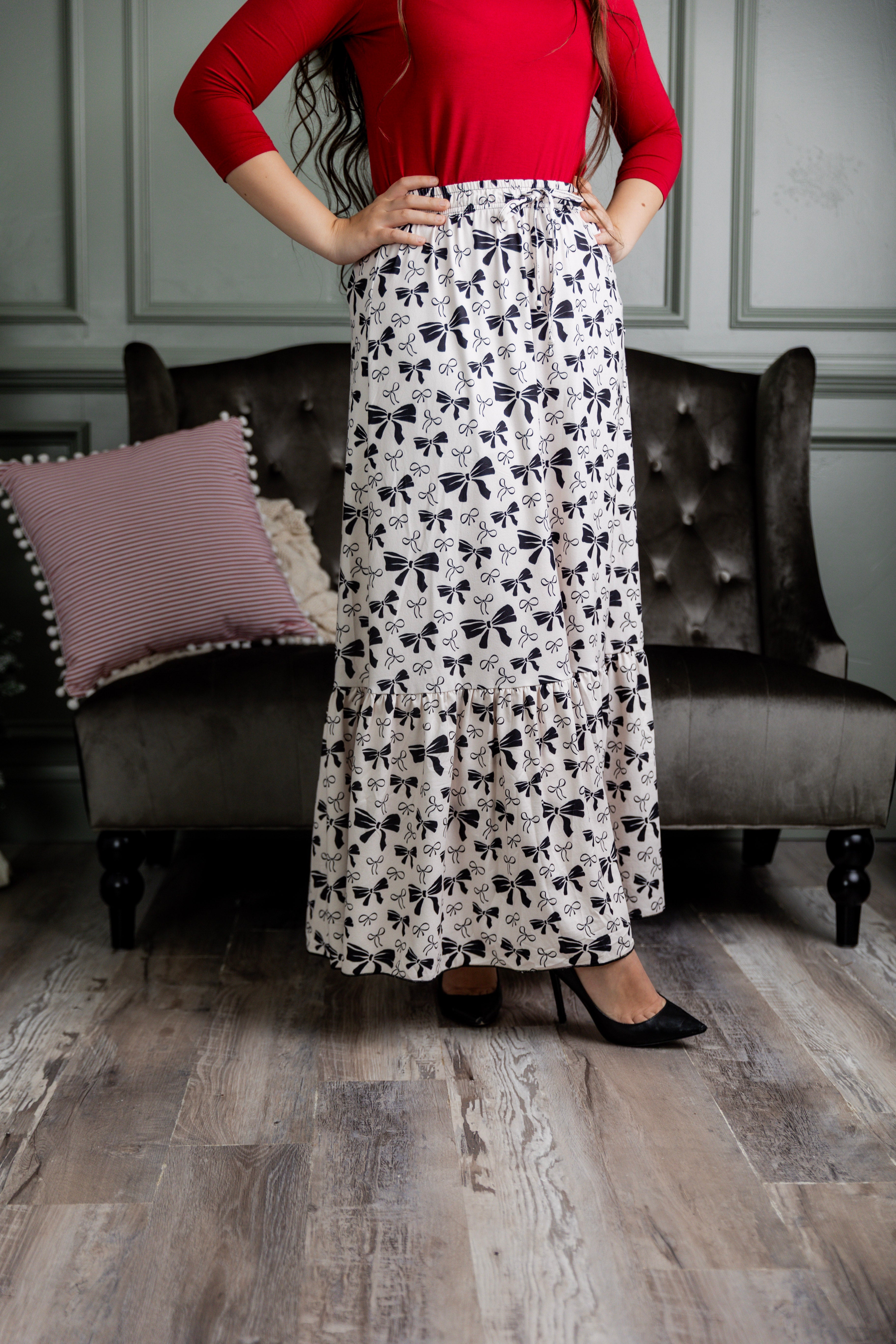 Model wearing the Nuggles® Sage Skirt in white with black bow print, featuring a gathered tiered hem and adjustable drawstring waist.