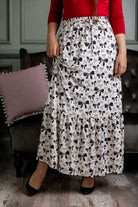 Model wearing the Nuggles® Sage Skirt in white with black bow print, featuring a gathered tiered hem and adjustable drawstring waist.