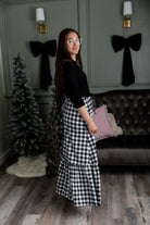 Model wearing the Nuggles® Sage Skirt in black and white gingham, featuring a tiered ruffle hem and drawstring waist.