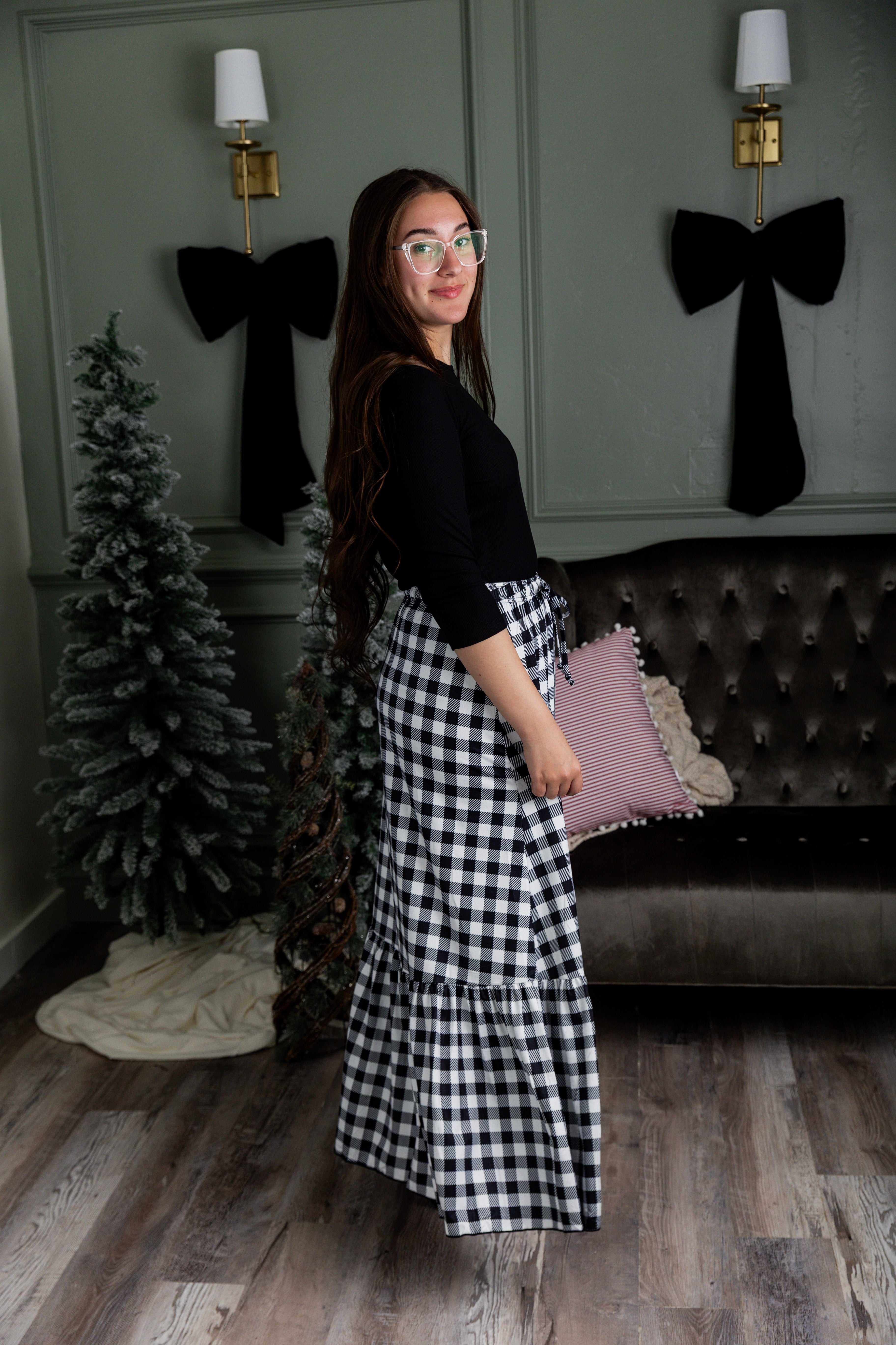 Model wearing the Nuggles® Sage Skirt in black and white gingham, featuring a tiered ruffle hem and drawstring waist.