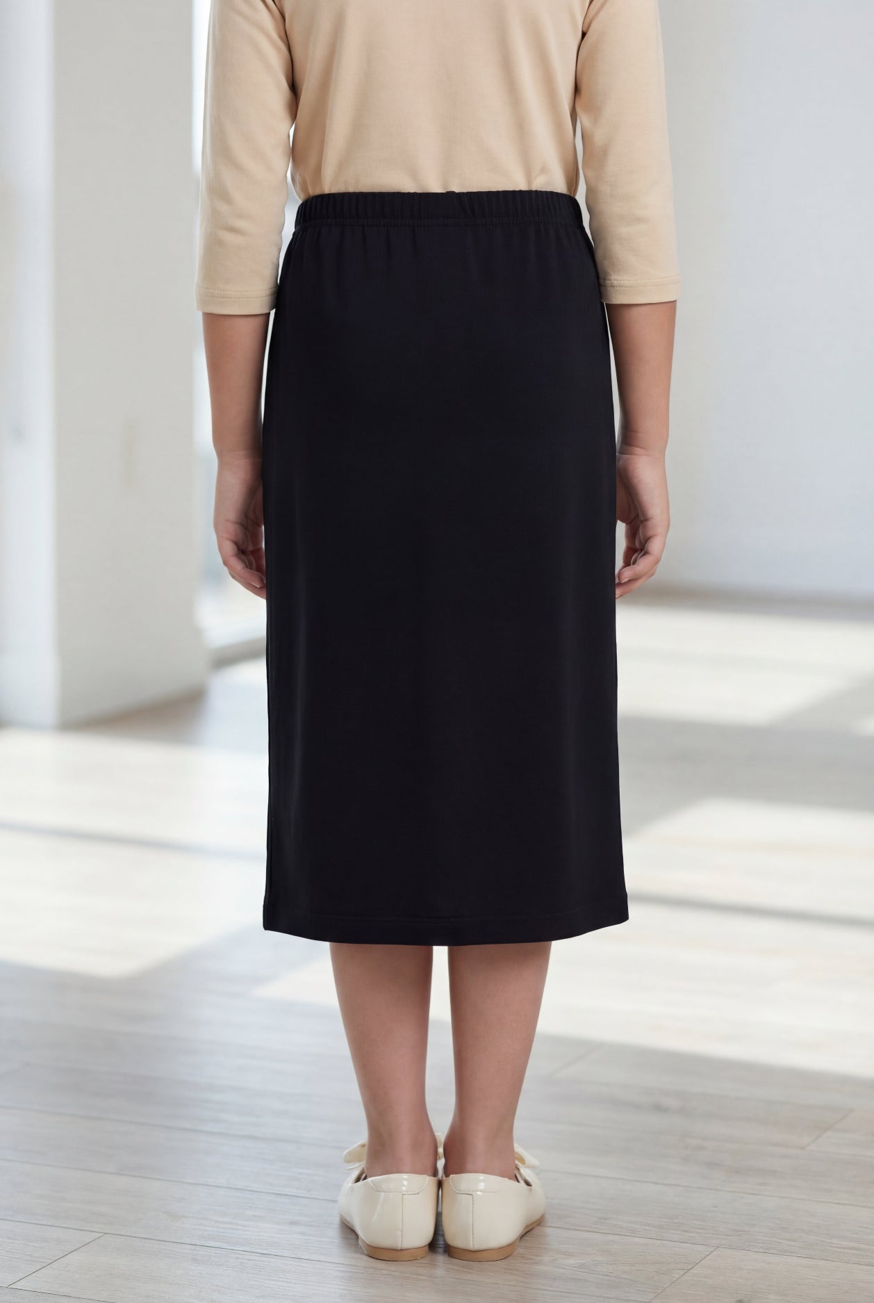 Model wearing the Nuggles® Girls' Classic Midi Skirt in Black